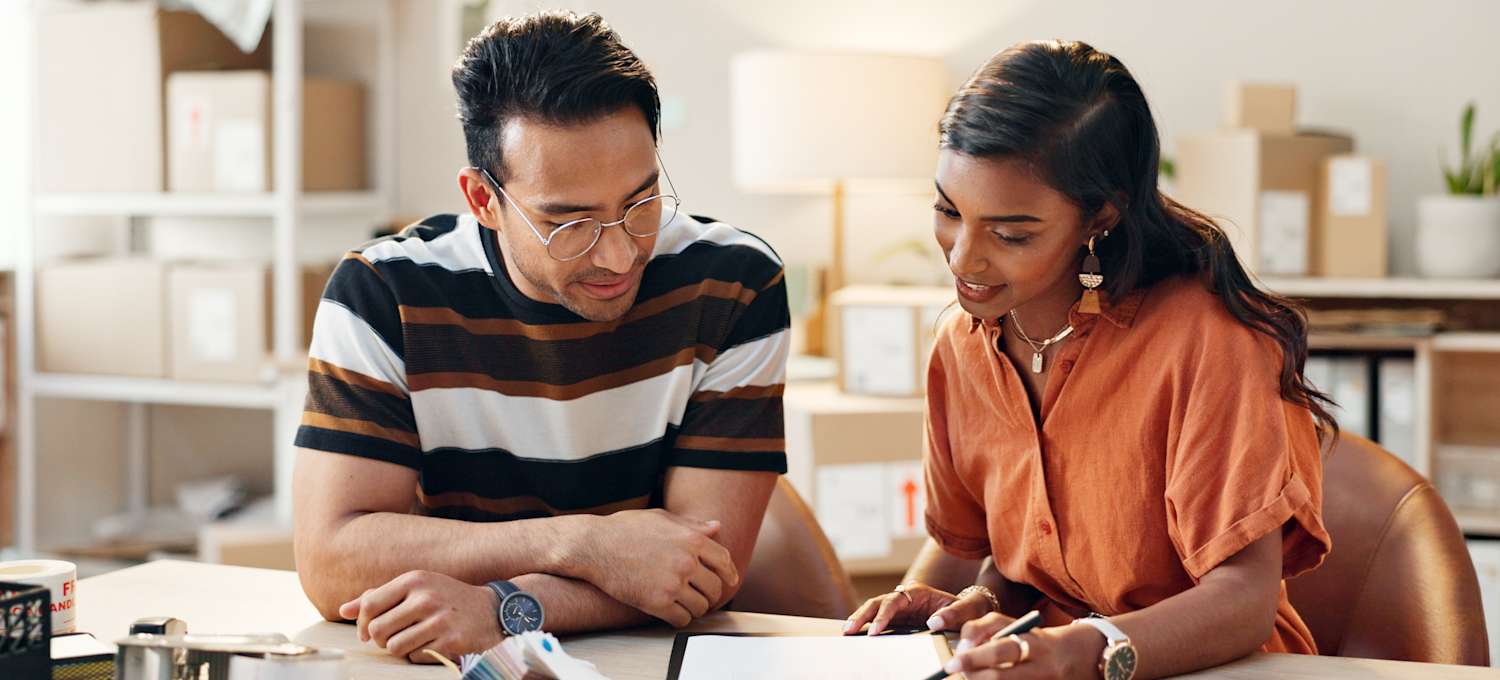 Two professionals discussing documents at a desk.