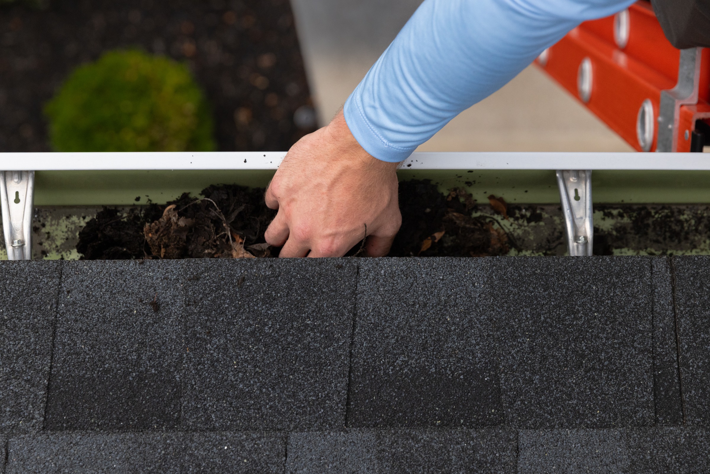 Technician cleaning dirt out of gutter