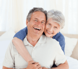 A happy elderly couple hugging and smiling.
