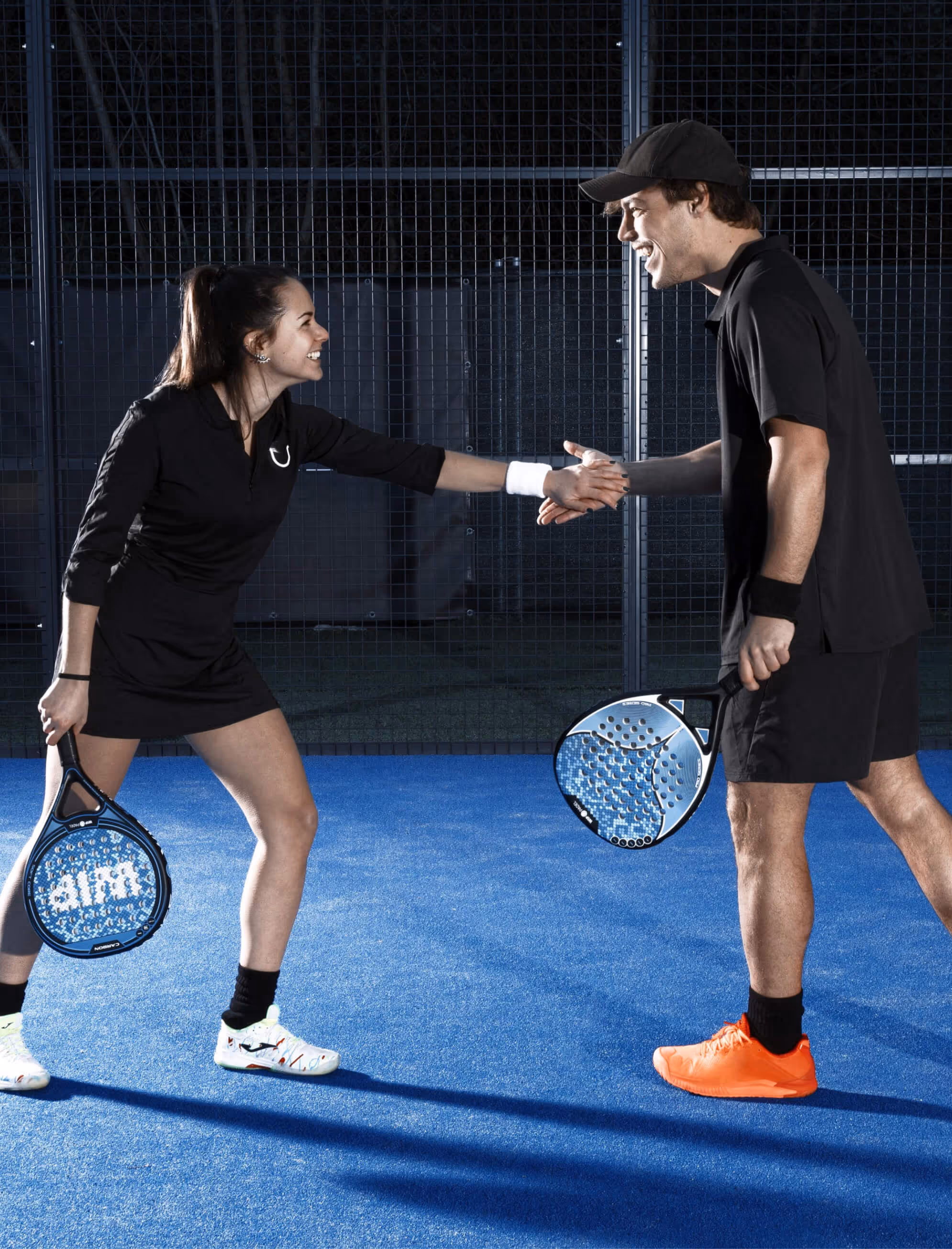 Vrouw en man schudden hand op padelbaan