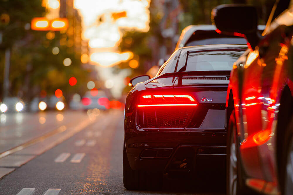 Rear view of a sports car with illuminated taillights in evening traffic.
