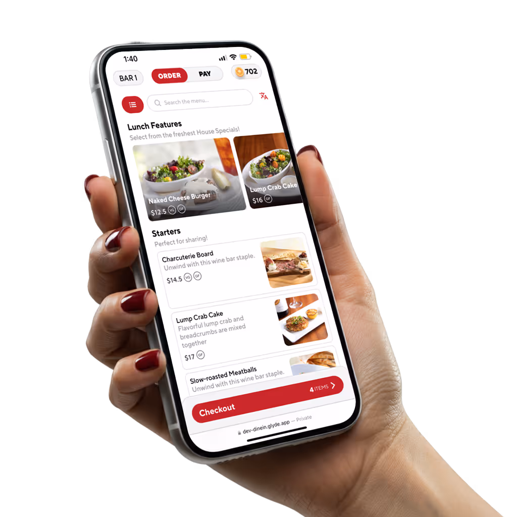 Hand holding smartphone displaying a food ordering app with lunch specials and starters menu including Naked Cheese Burger and Lump Crab Cake.