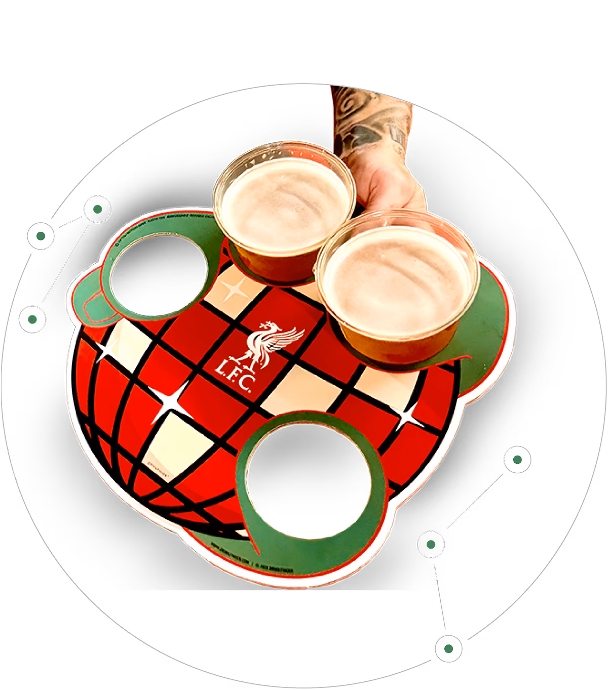 A tattooed hand holds two cups of beer in a Liverpool FC branded cardboard beverage carrier with a red, black, and cream checkered pattern and green cup holders.