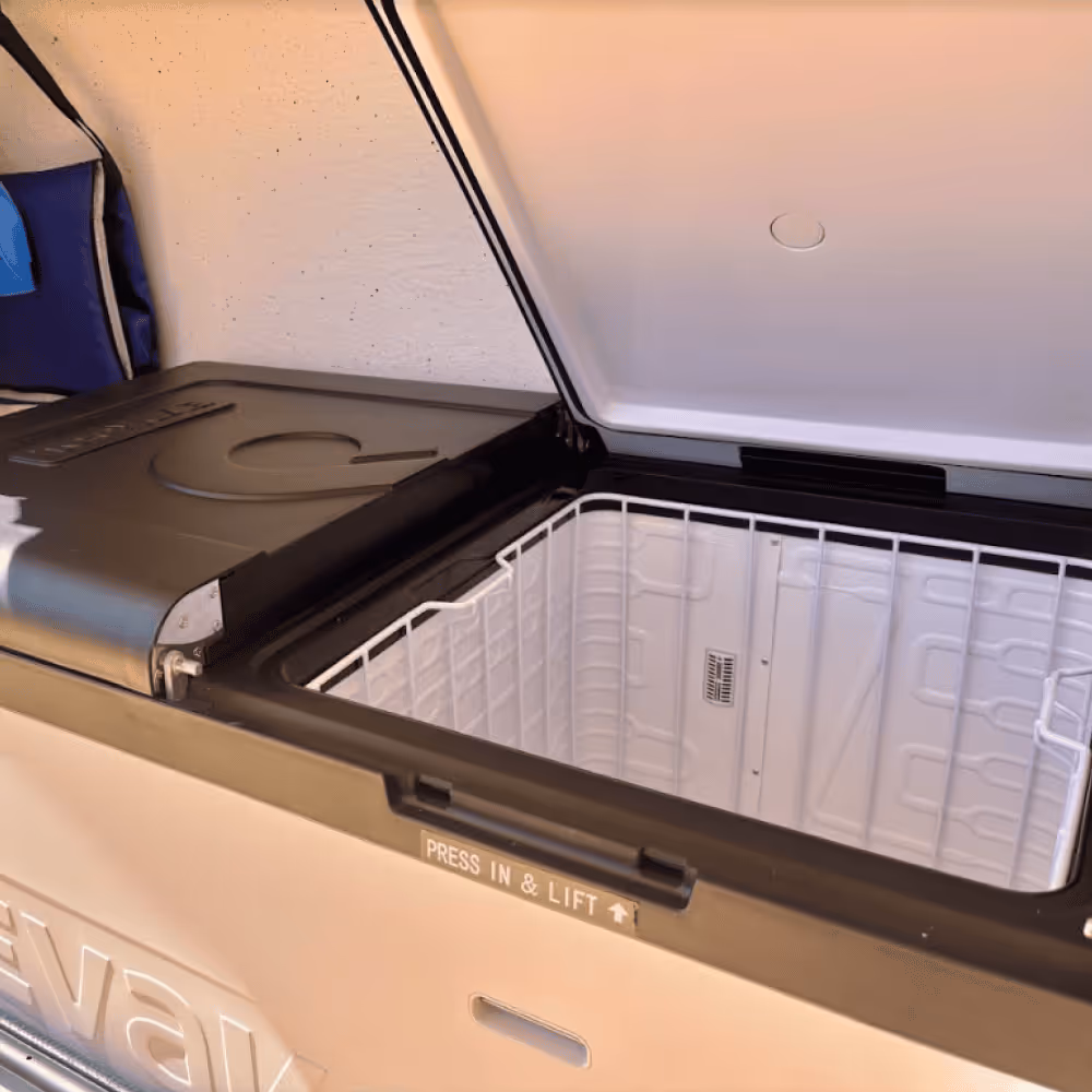 Open white and black portable cooler chest with a wire basket inside and 'Press In & Lift' label on the edge.