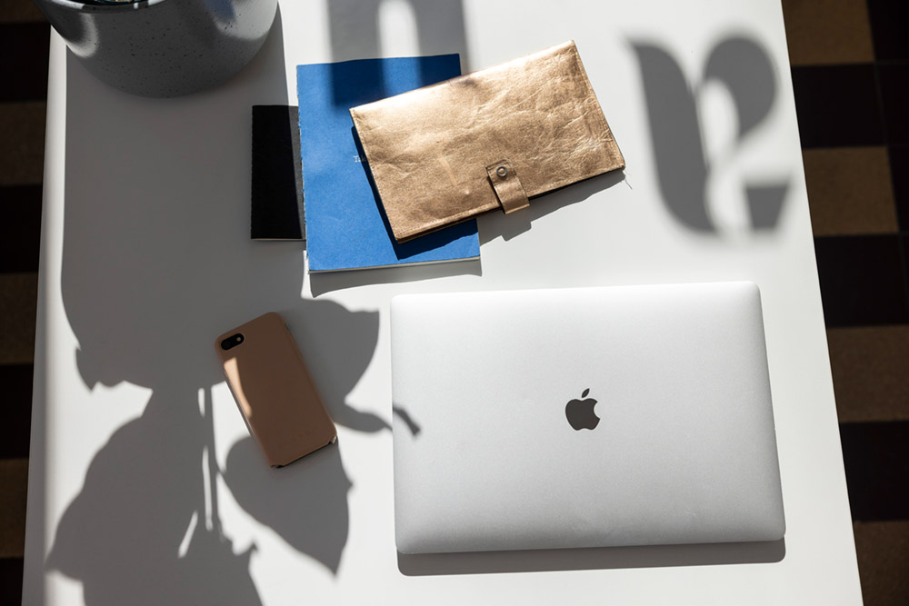 Laptop, Handy, Notizheft von oben. Die Arbeitsmaterialien.