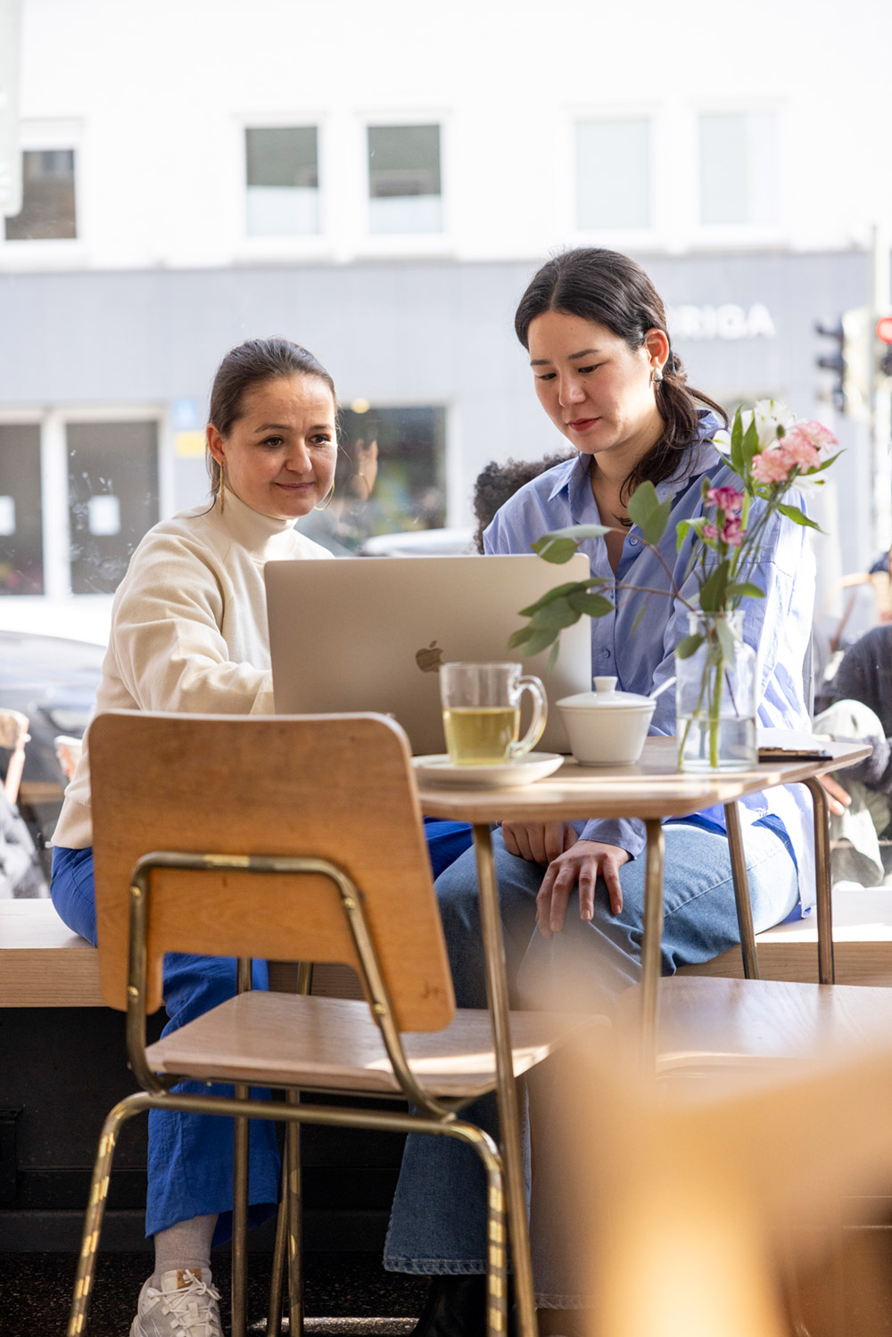Asuka Grün und Julia Weikinn in einem Kaffee am Laptop bei der gemeinsamen Arbeit.