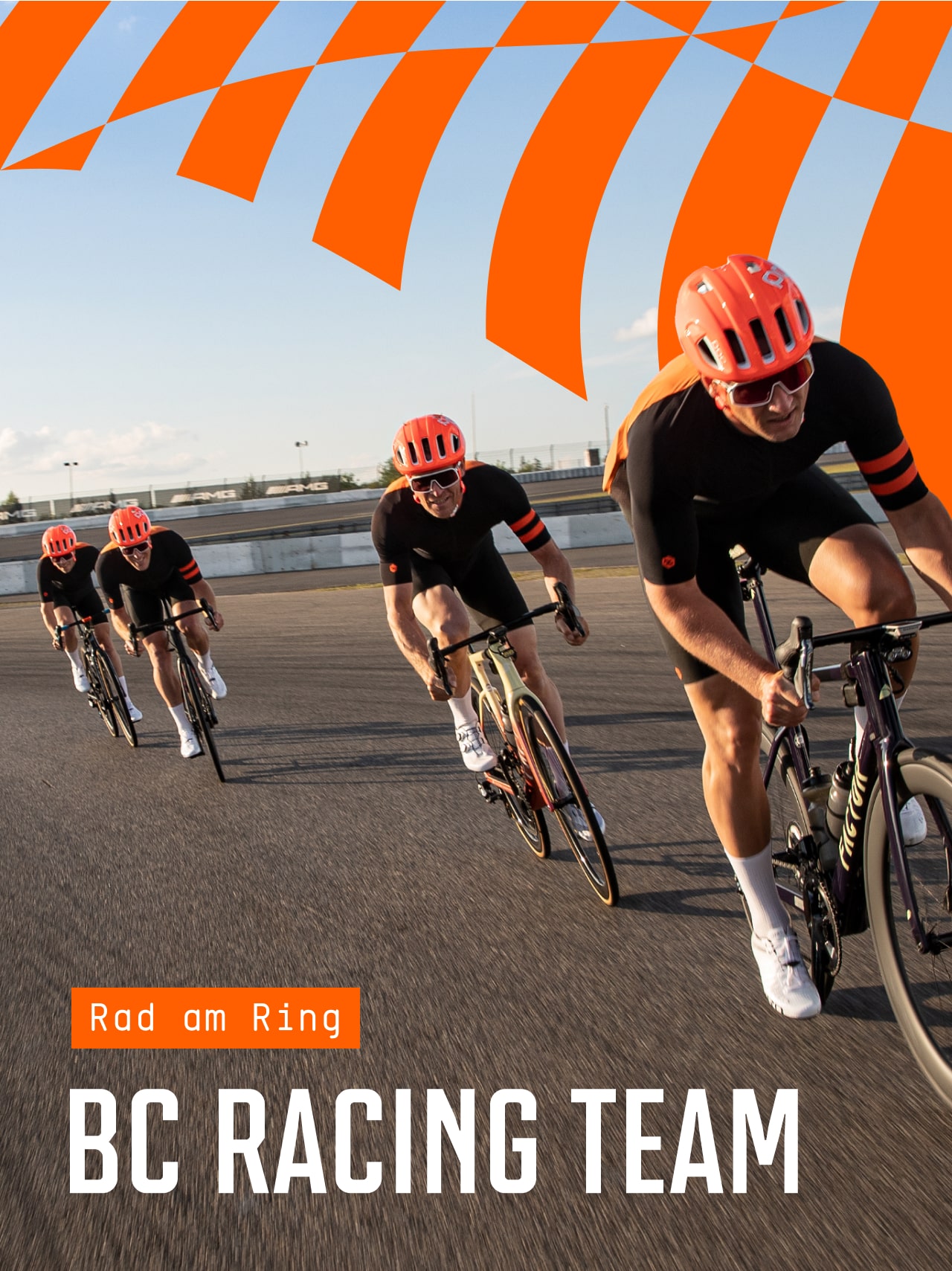 Vier Radfahrer in passender schwarzer Kleidung und orangefarbenen Helmen fahren eng beieinander auf einer Straße, über der ein orangefarben gemustertes Transparent hängt. Der Text lautet: Shut up Riding BC Racing Team".