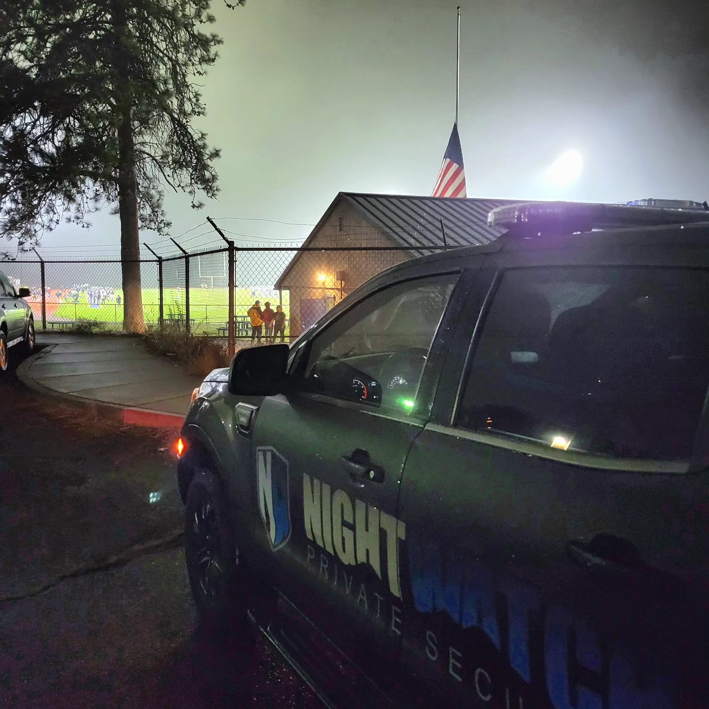 A security truck parked outside a football stadium at night.