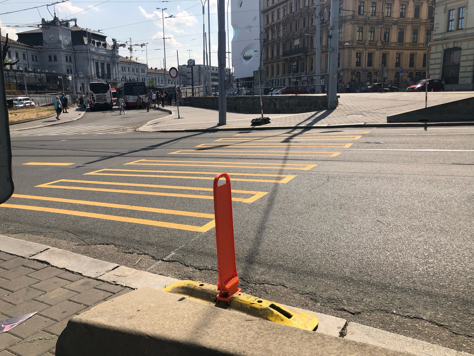 Fotka náhradního přechodu vyznačeného žlutou páskou, na jeho začátku i konci je vysoký obrubník.