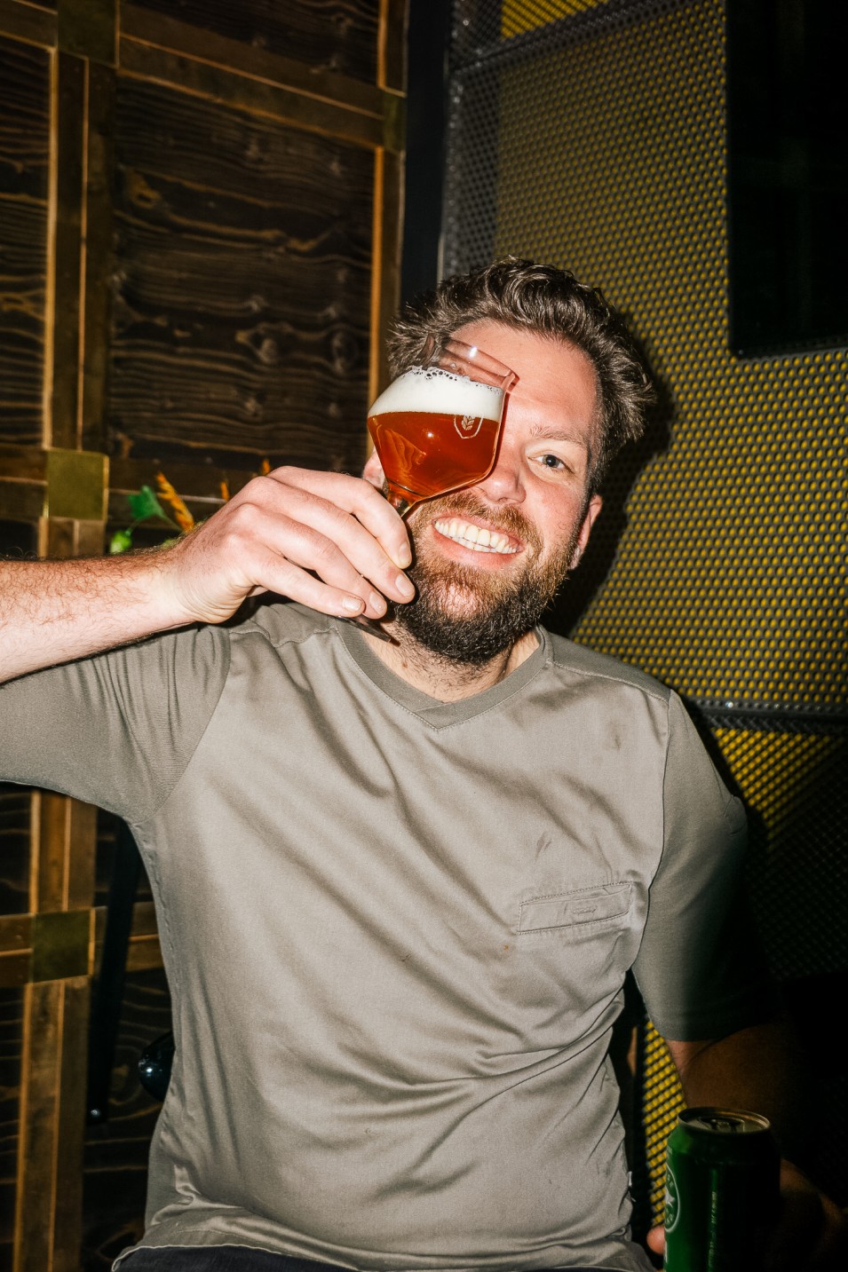 Lachende man houdt een glas bier voor zijn oog