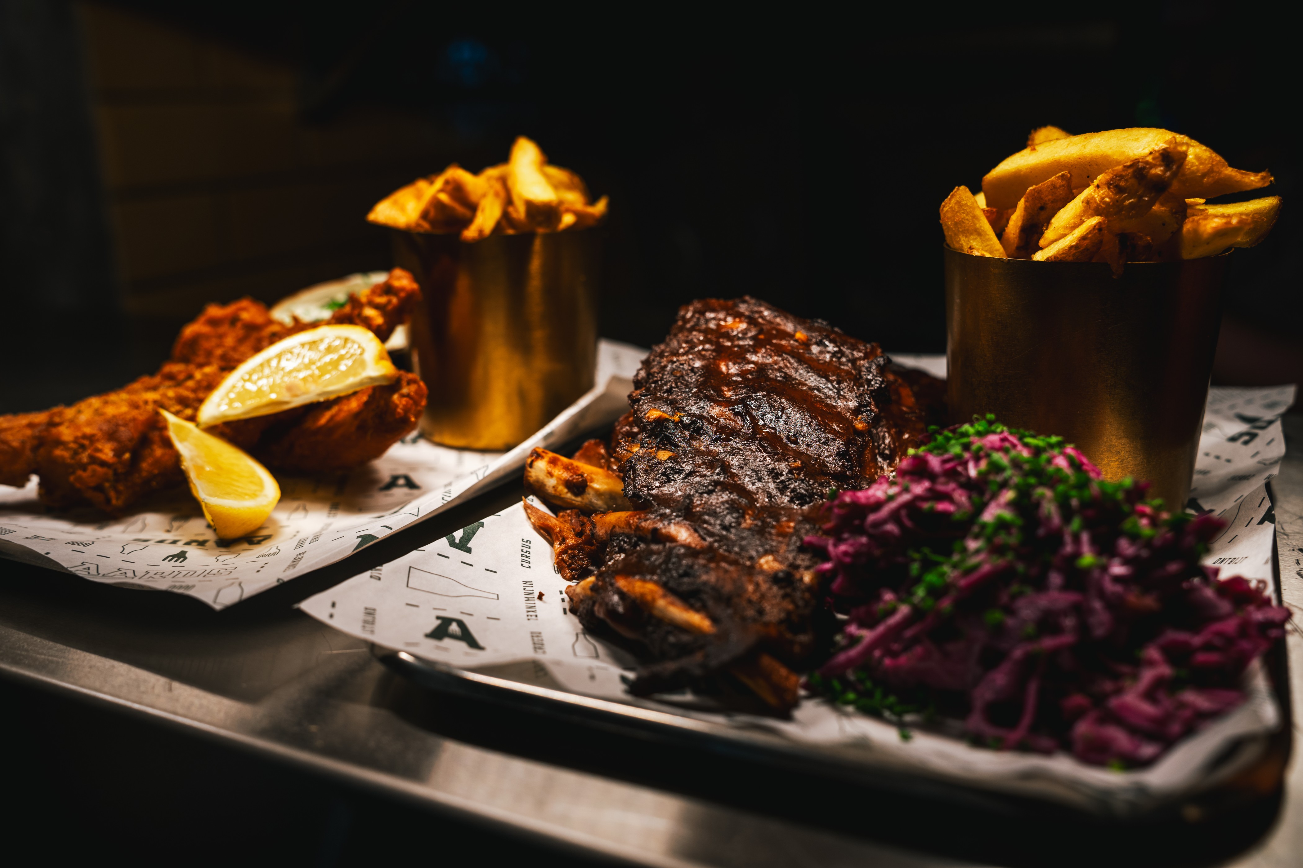 Spareribs met rode koolsalade, friet in gouden bakjes en gefrituurde vis met citroen