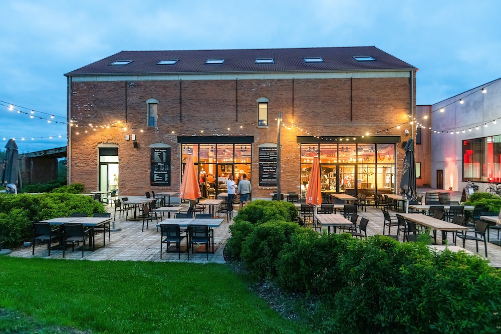 Brouwerijgebouw met terras en lichtslingers in de avondschemering