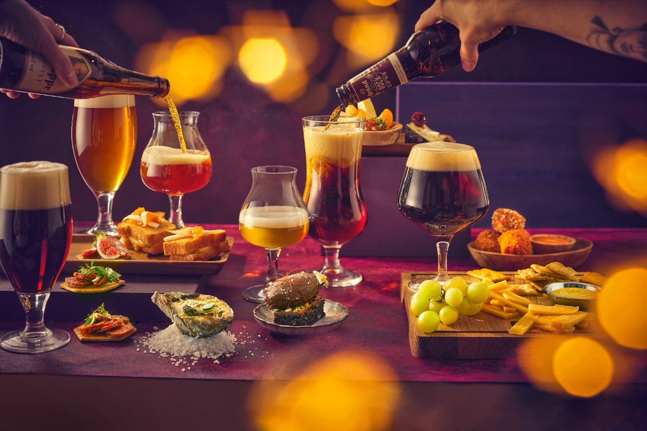 Handen schenken bier in glazen boven een tafel met bier en bites
