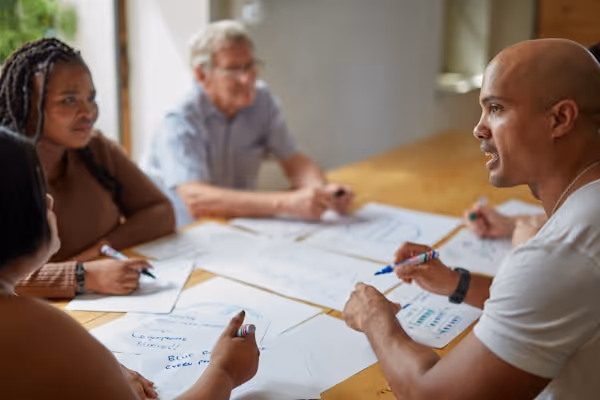 People are collaborating on papers at a table.
