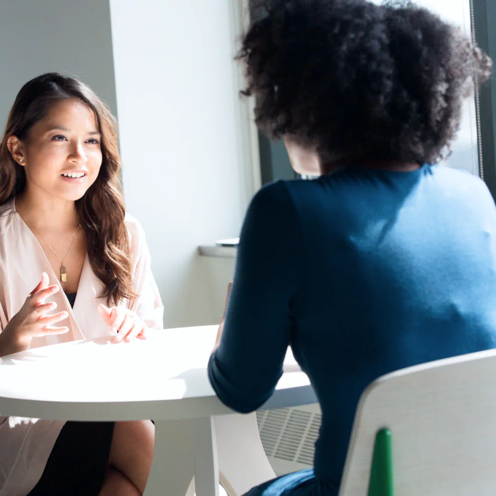 a woman sitting at a table talking to another woman - volunteer - best organization website webflow CMS template