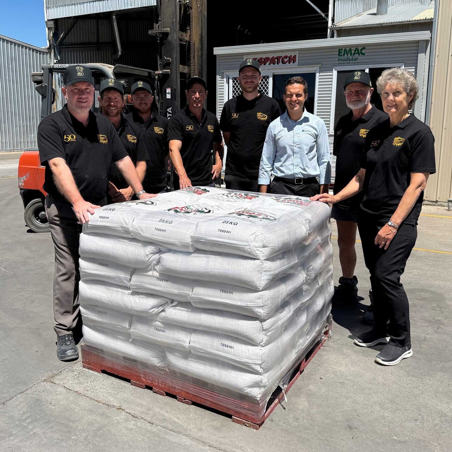 Tatiara Seeds team standing beside a pallet of bagged seed at their Bordertown facility.