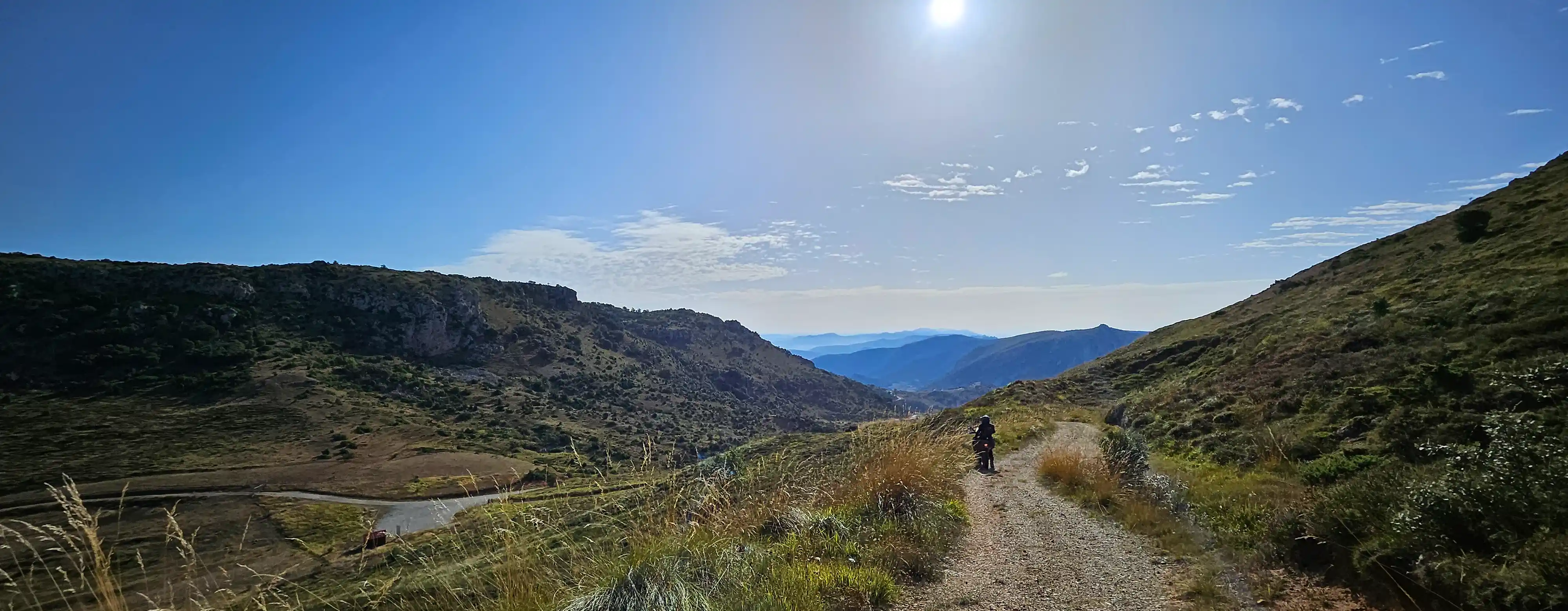 Pilote de moto trail seul sur une piste de crête face aux montagnes