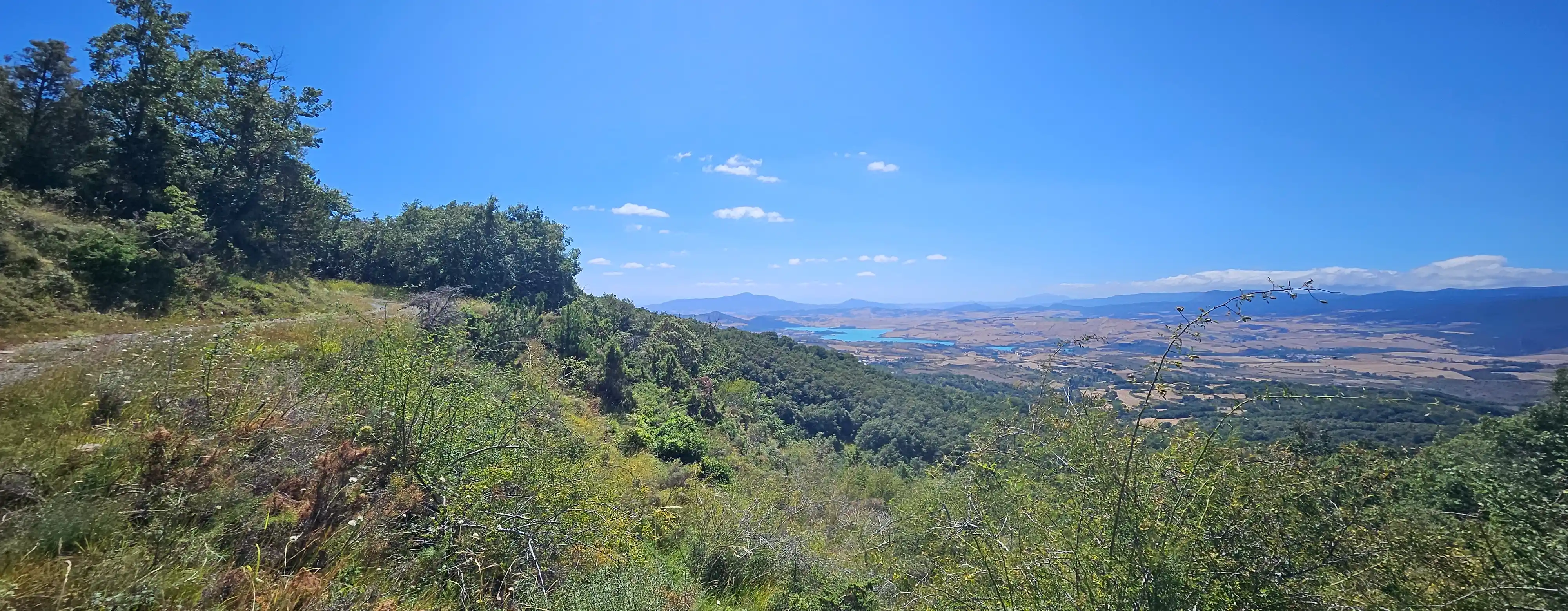 Panorama sur une vallée et un lac depuis une piste de montagne