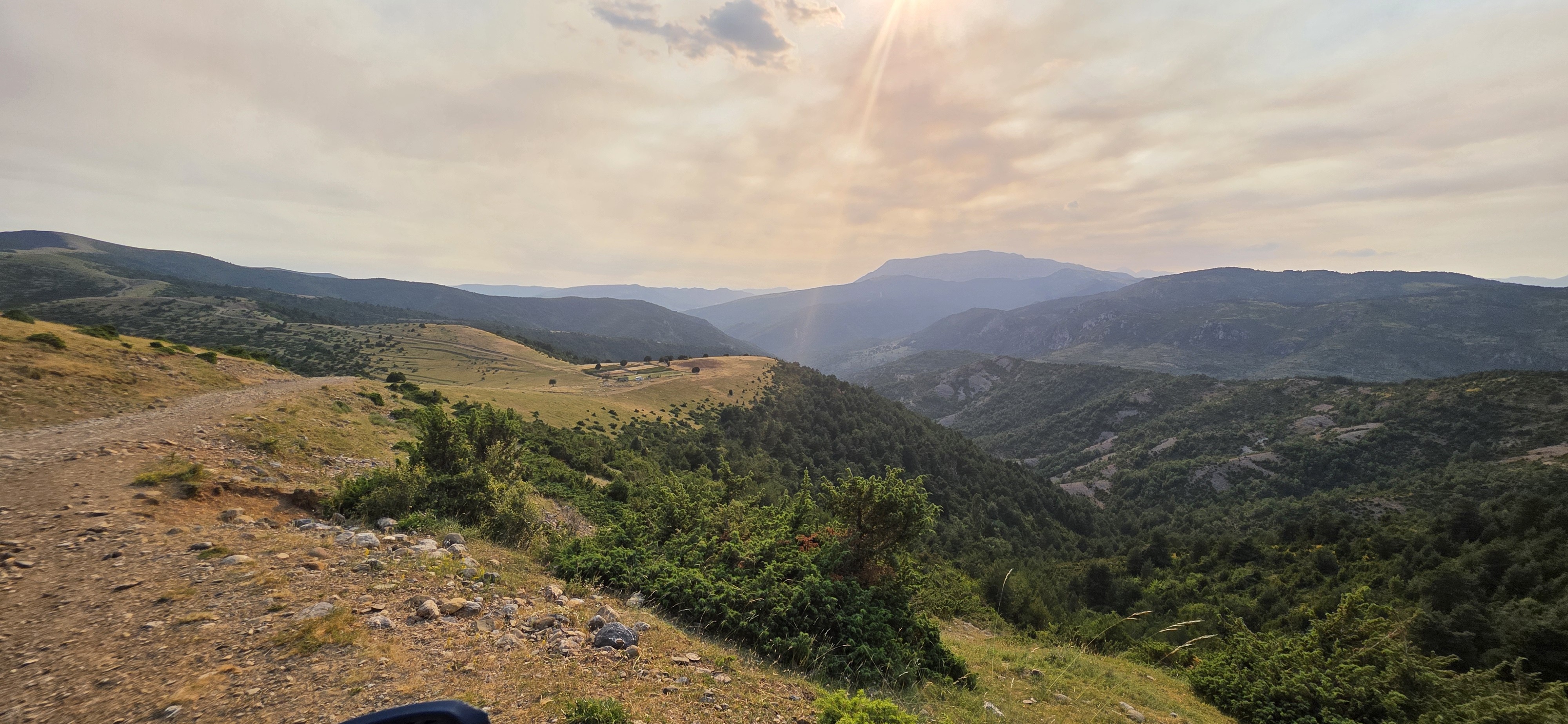 Panorama sur des vallées boisées depuis une piste de crête au coucher du soleil