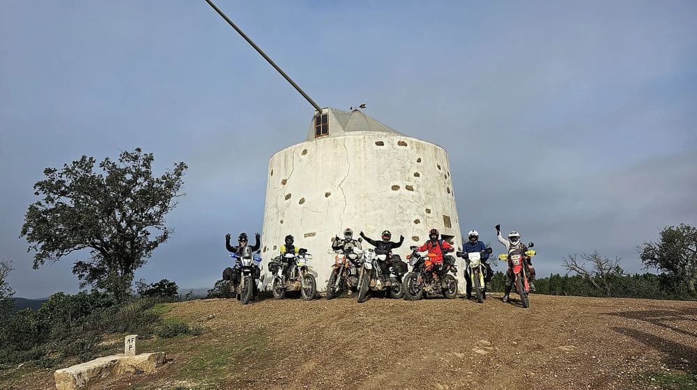 Groupe de motards trail devant un ancien moulin blanc