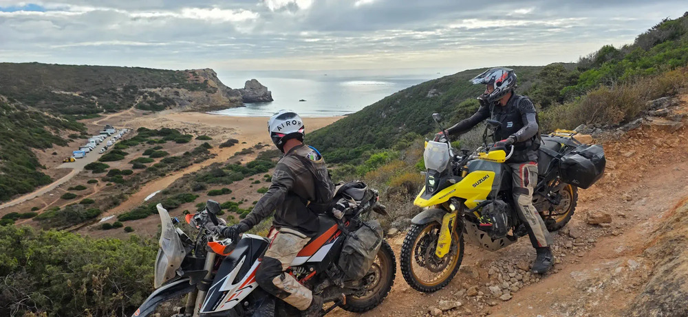 Deux motards en trail chargés sur une piste dominant une baie