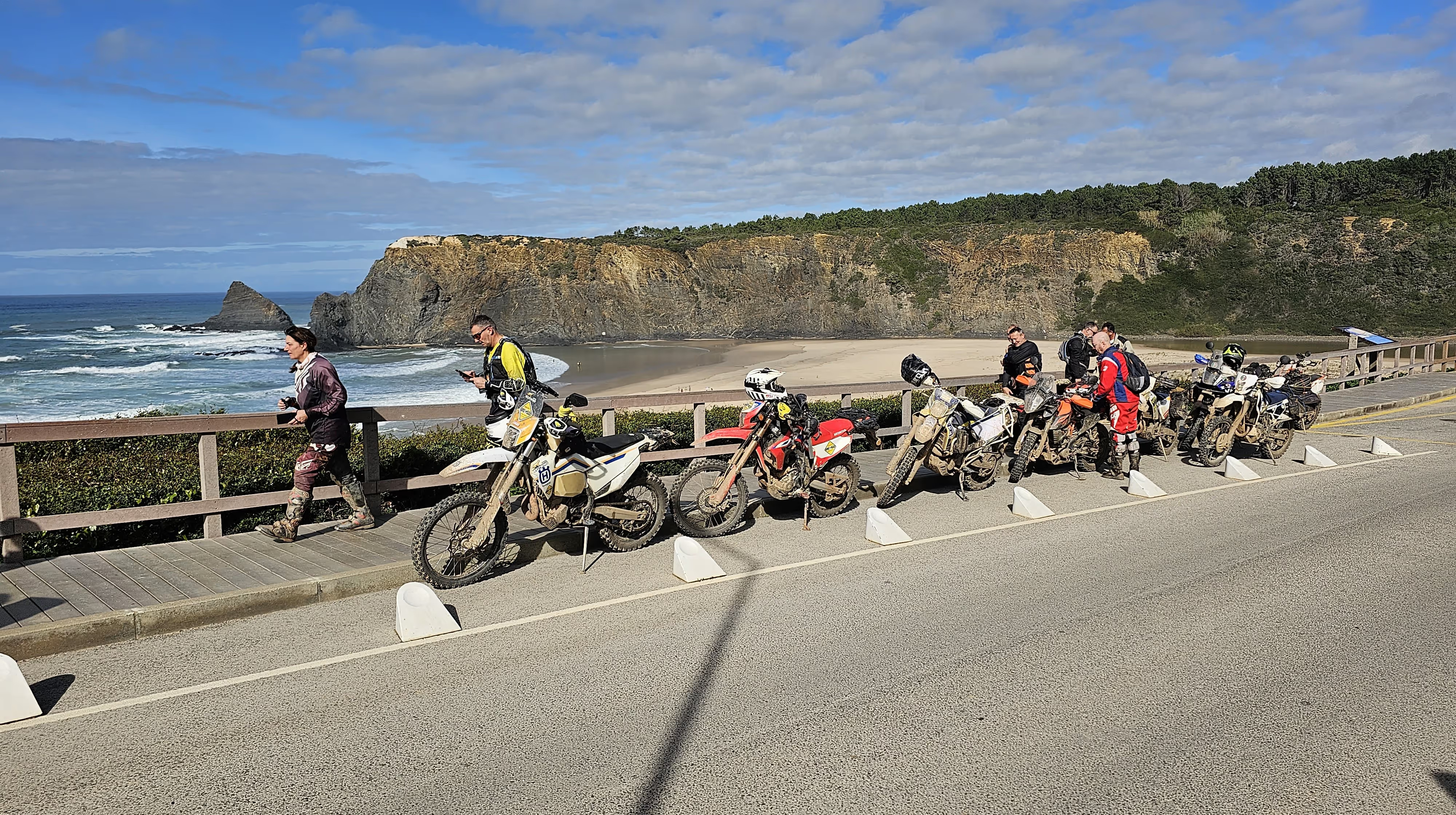 Groupe de motos garées le long d’une route côtière face à la mer