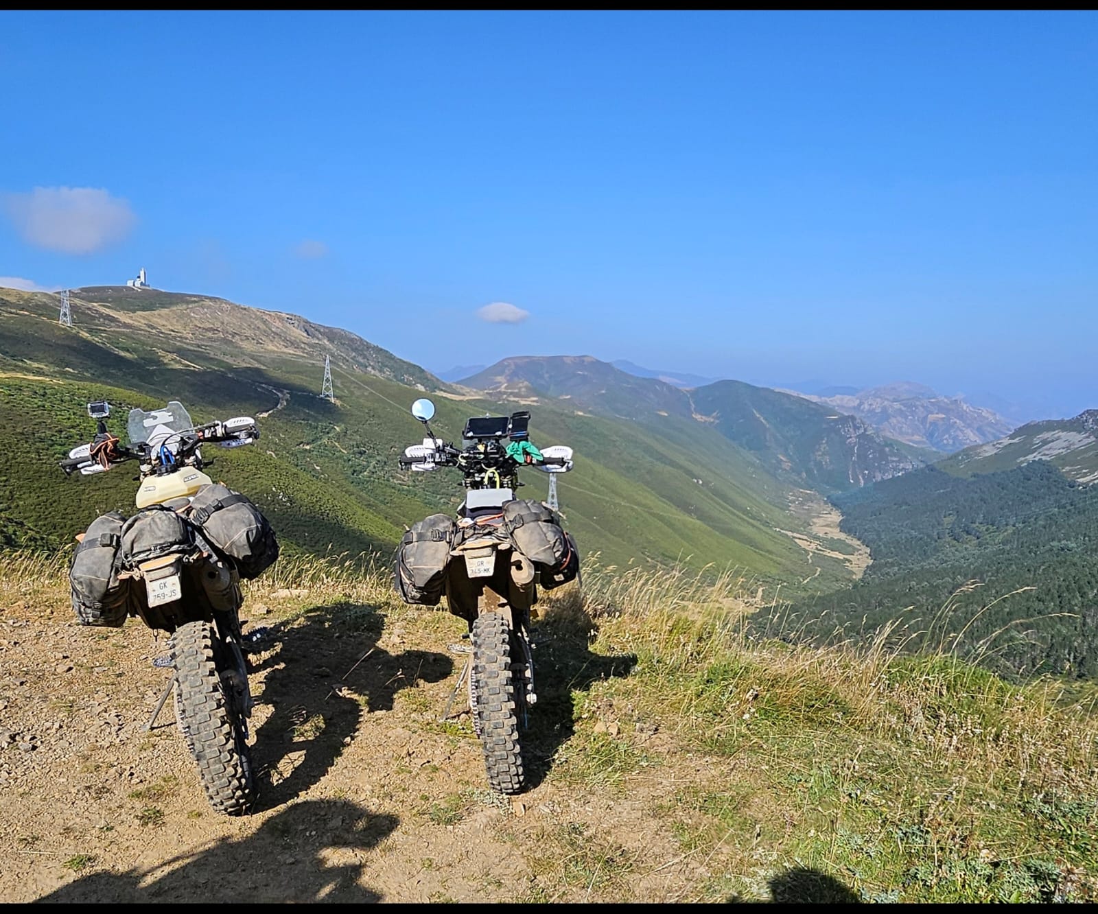 Deux motos trail chargées garées face à une vallée de montagne