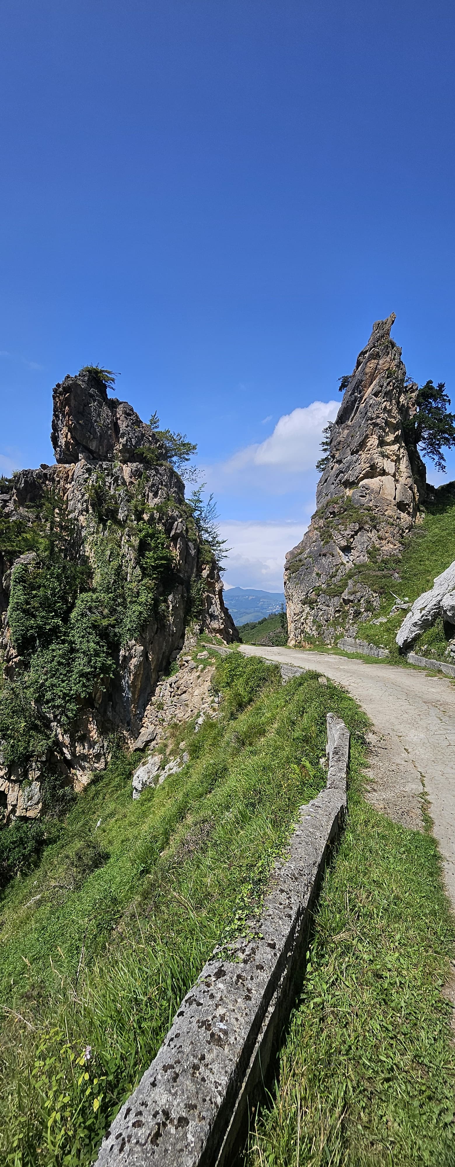 Piste étroite longeant des aiguilles rocheuses sous un ciel bleu
