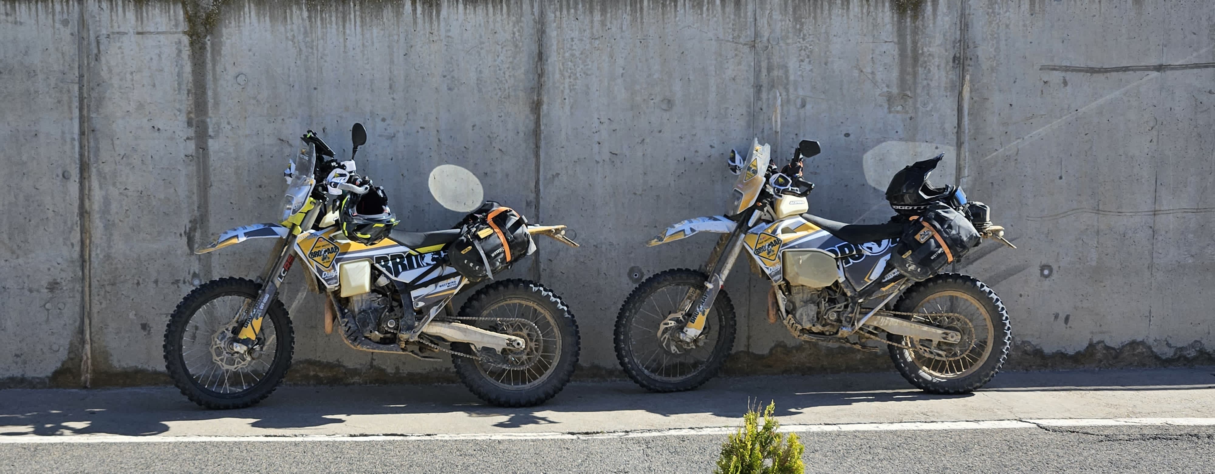 Deux motos trail chargées garées contre un mur en béton