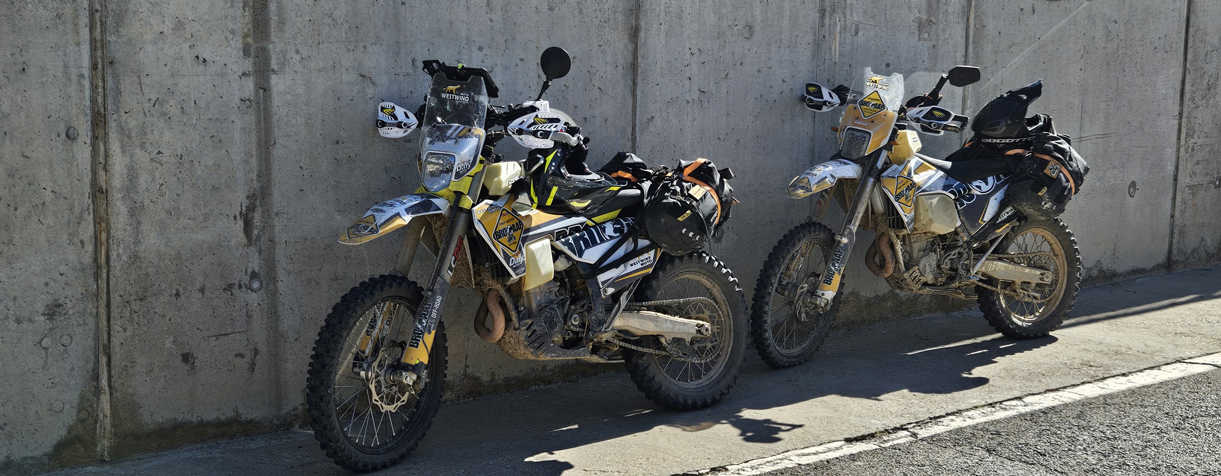 Deux motos trail chargées garées contre un mur en béton
