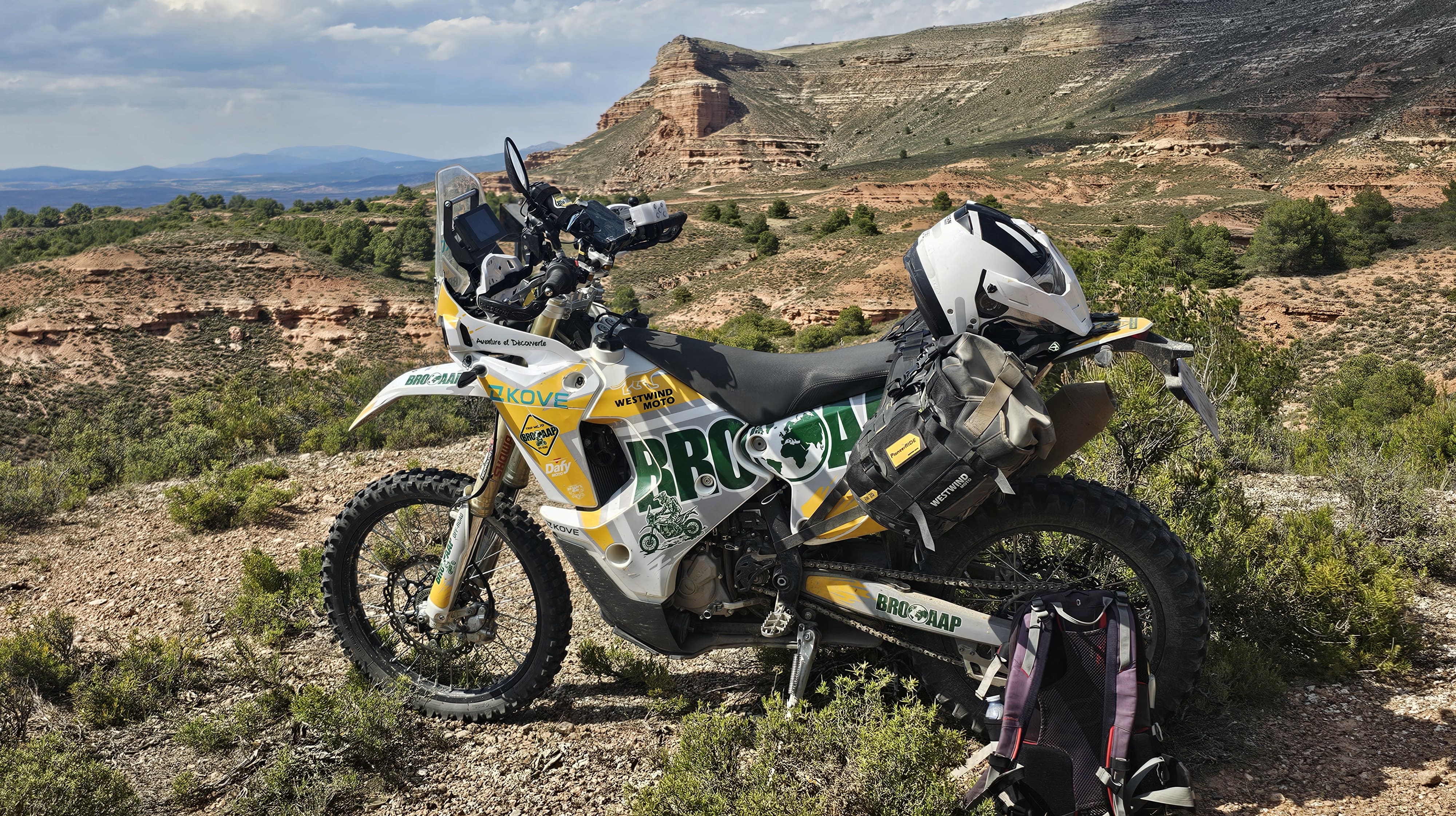 Moto trail Brooaap chargée garée face à des reliefs rocheux