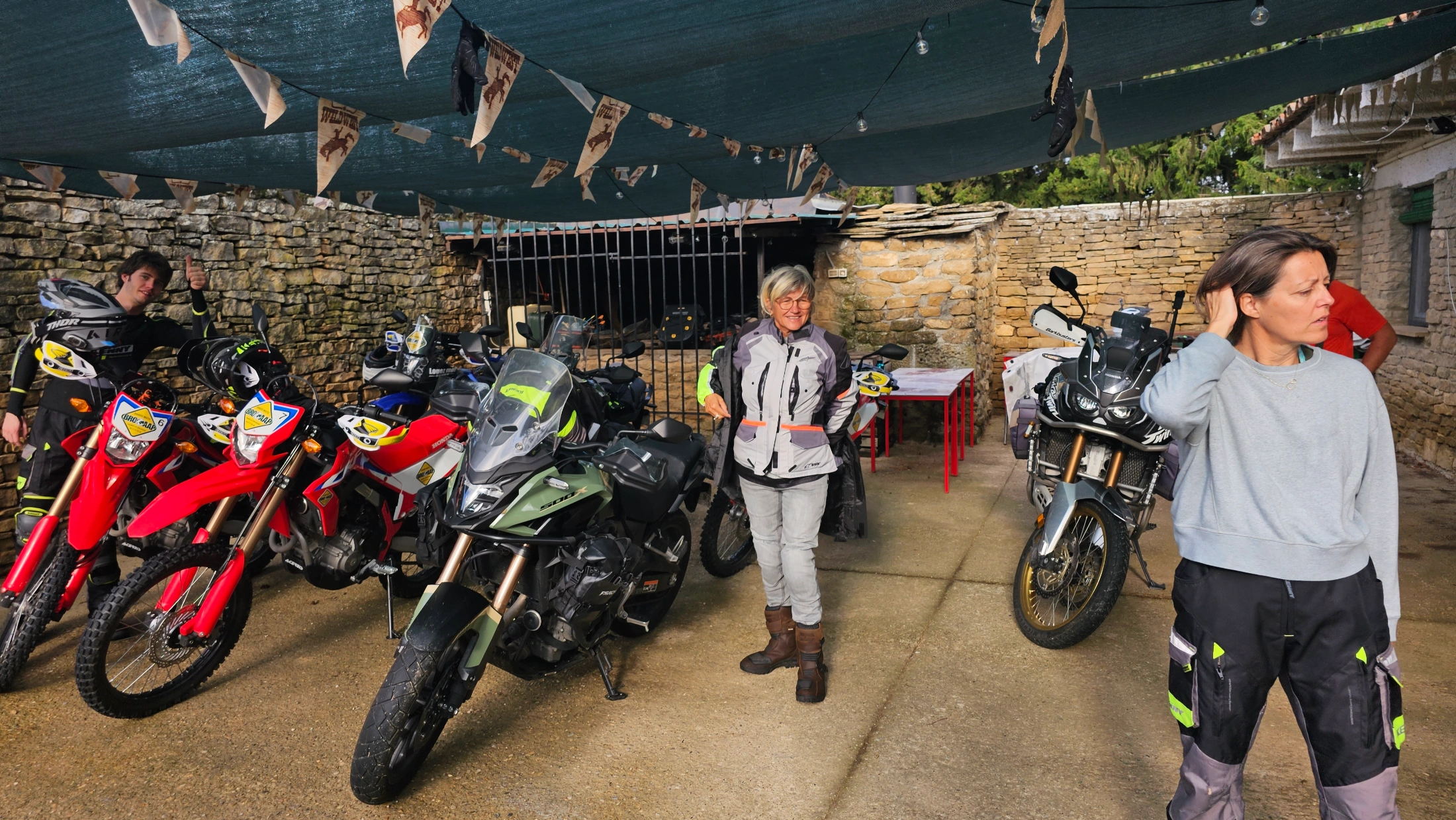 Motardes et motos d’enduro sous un abri décoré de fanions