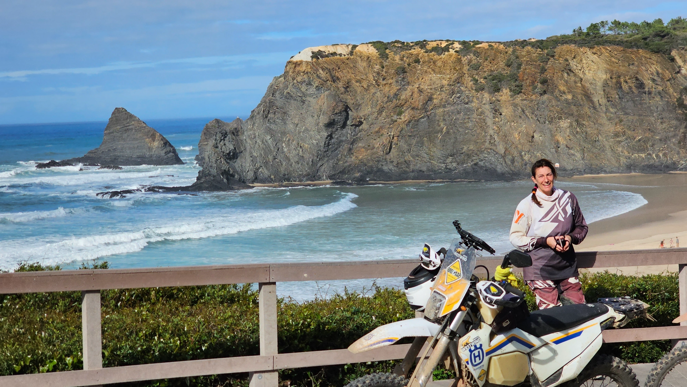 Motarde sur sa moto trail face à une falaise et à l’océan