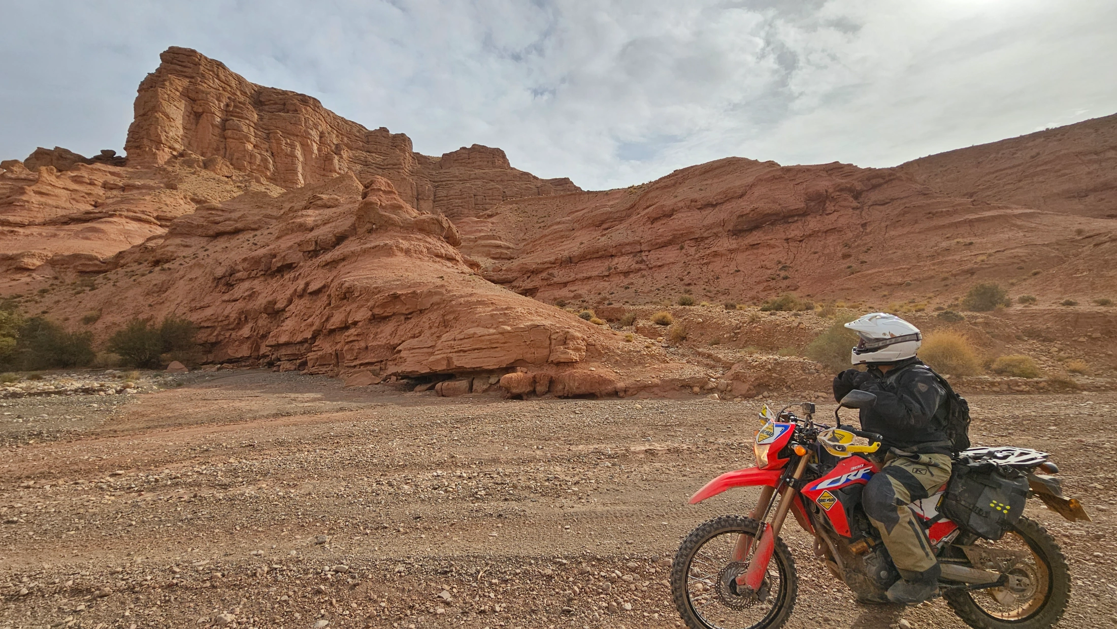 Motarde en moto d’enduro au pied de reliefs de terre rouge