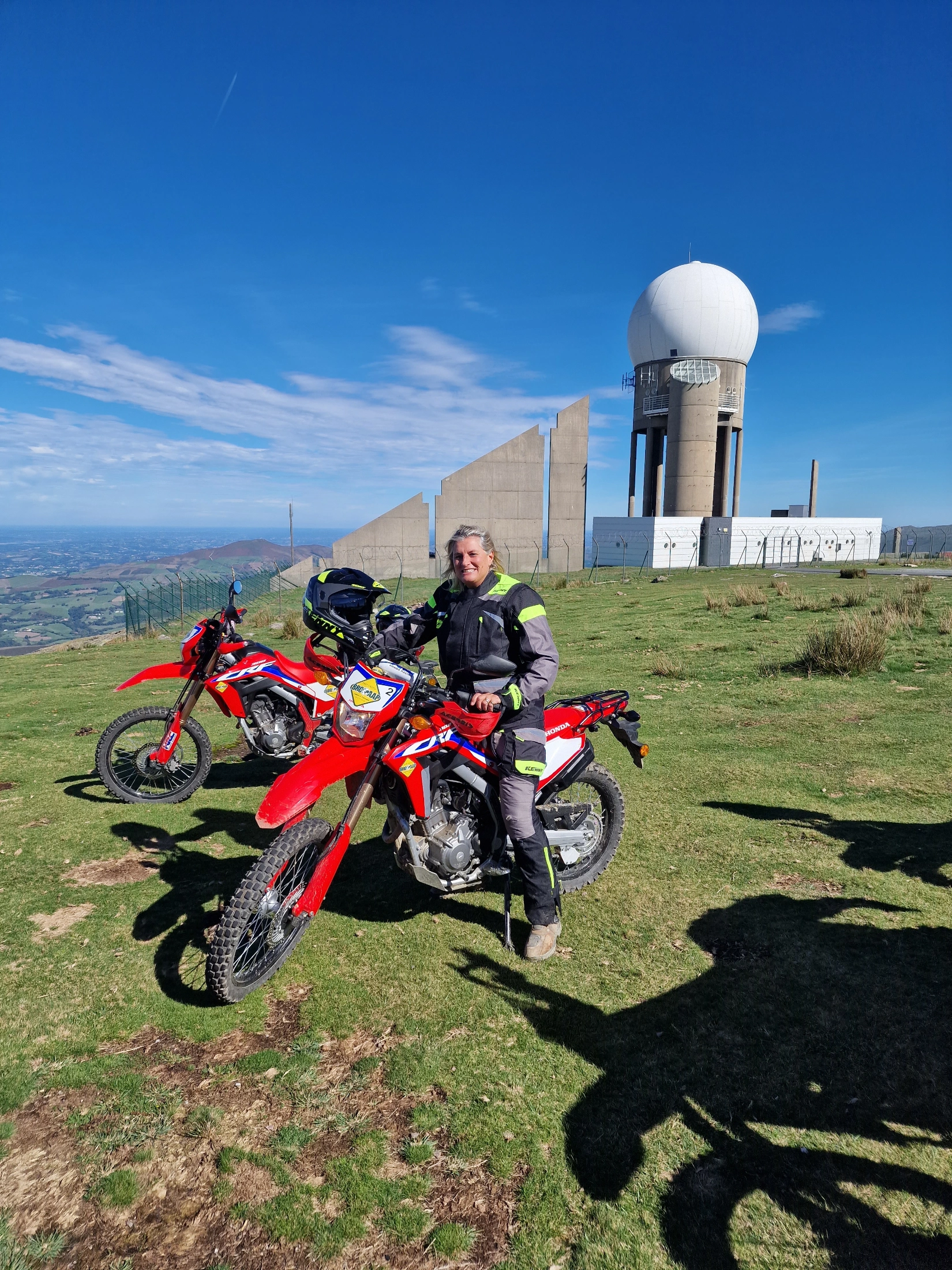 Motarde sur une moto d’enduro rouge près d’une station radar