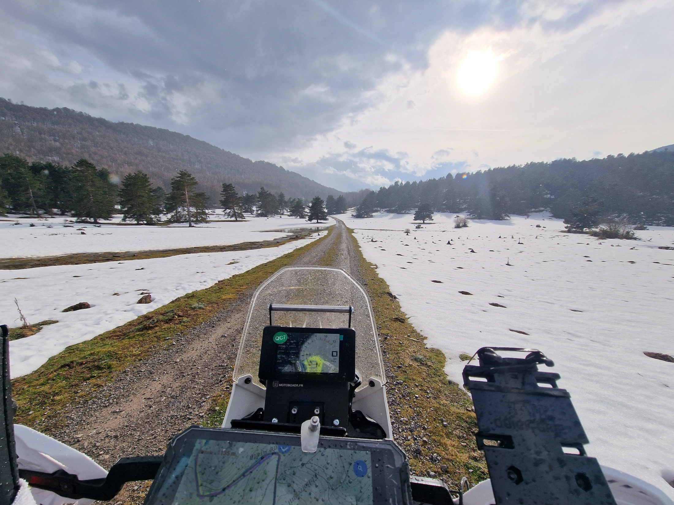 Piste enneigée vue depuis le guidon d’une moto trail équipée d’un GPS
