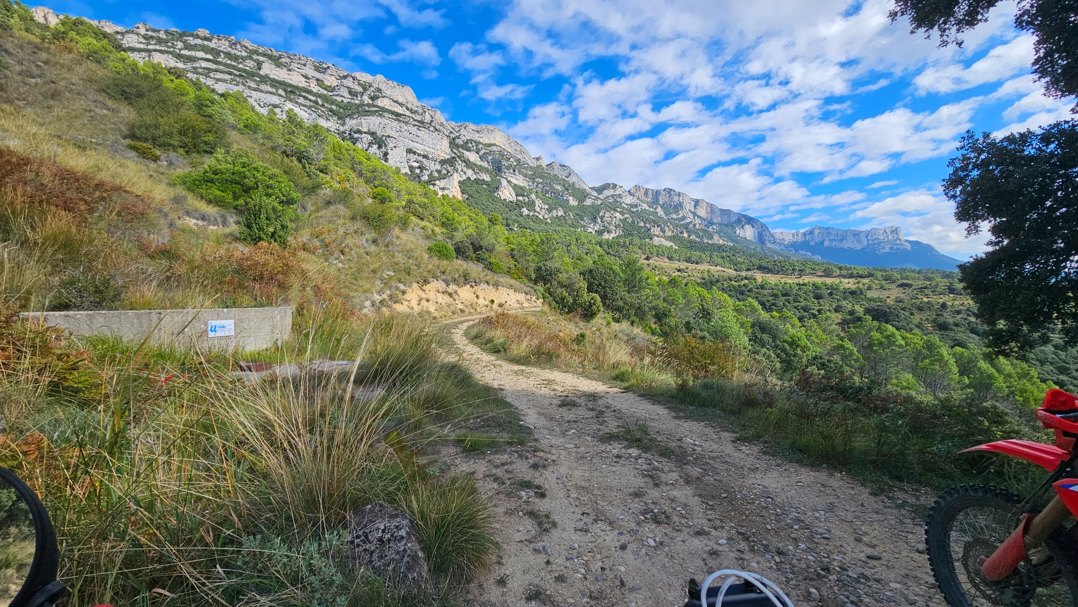 Piste de terre serpentant au pied d’une falaise calcaire