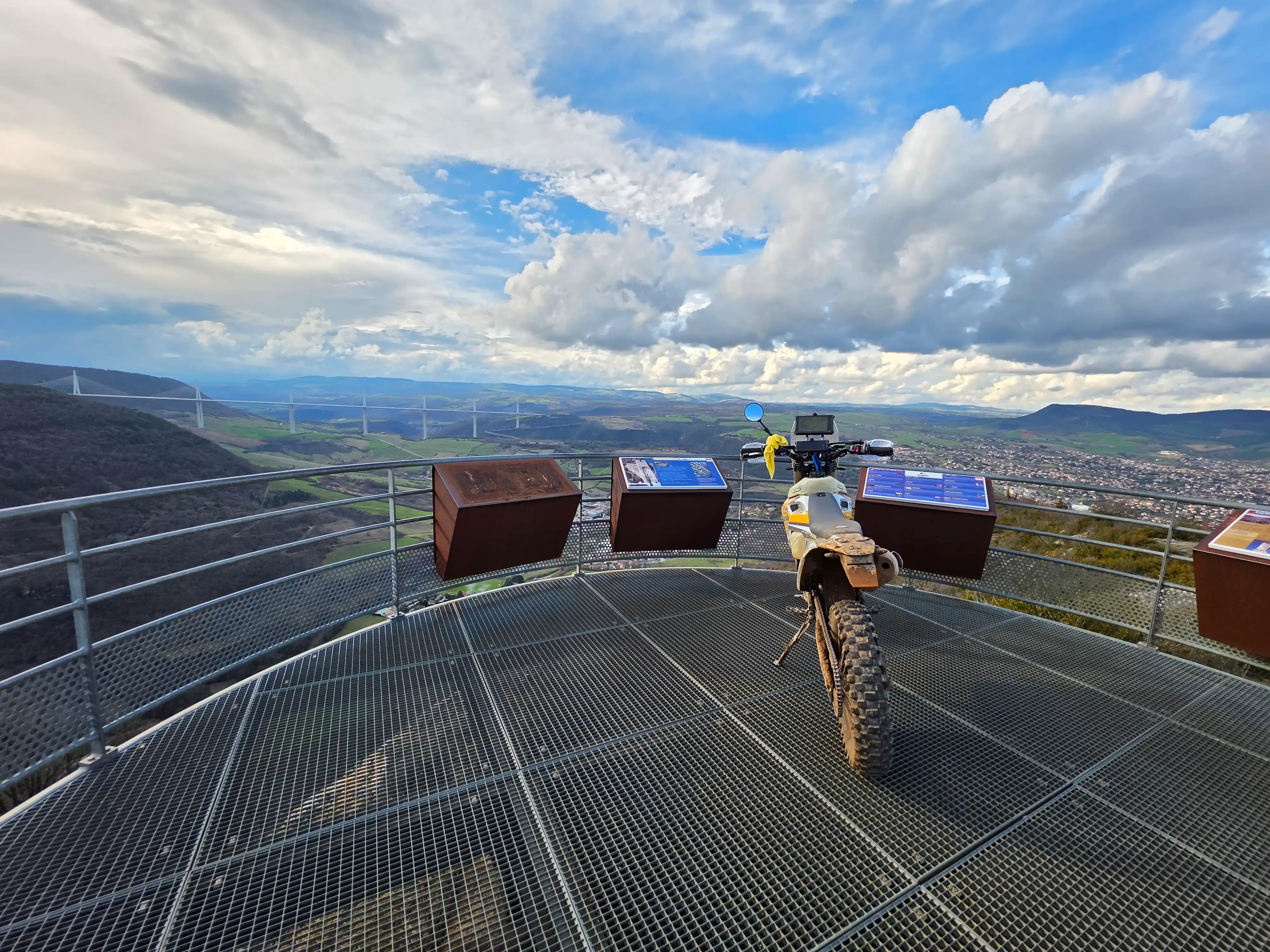 Moto trail sur une passerelle en caillebotis dominant la vallée