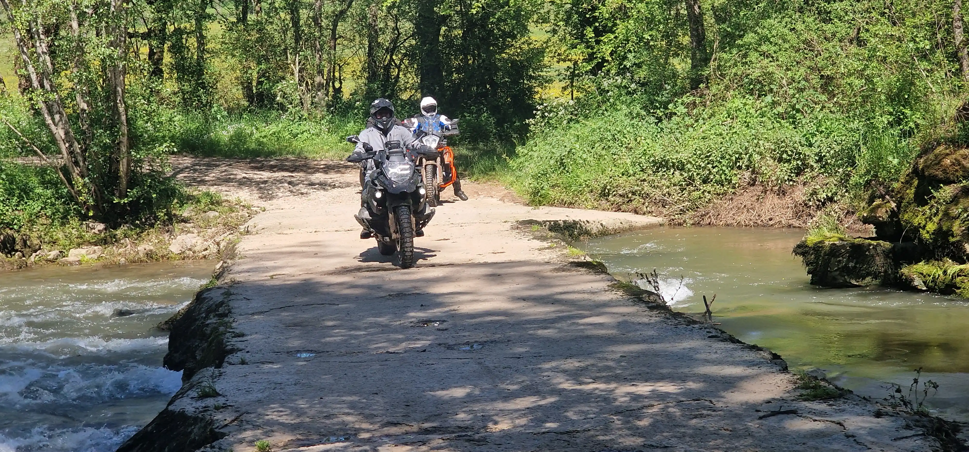 Motards trail franchissant un gué bétonné en forêt