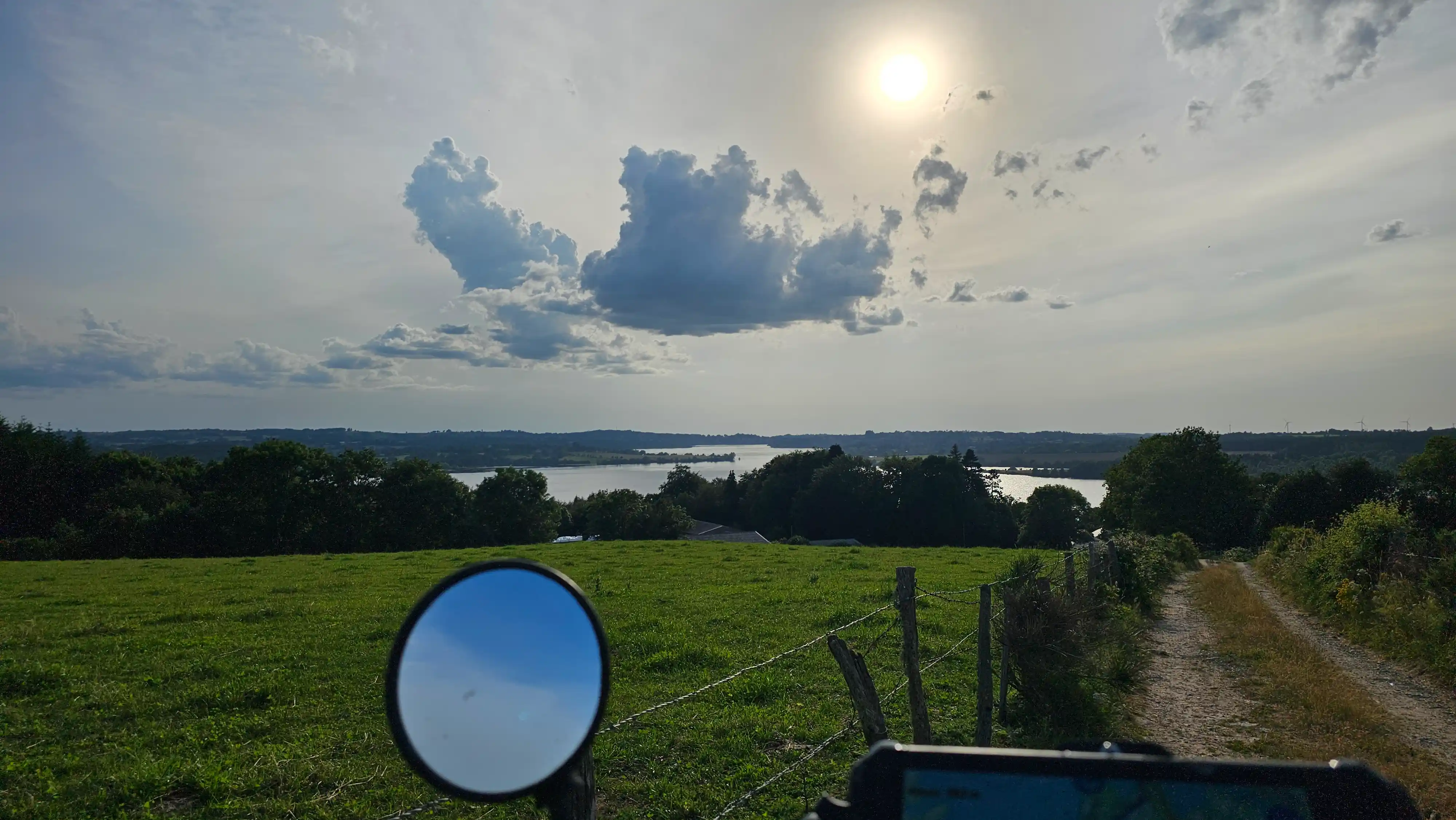 Prairie et lac vus depuis le rétroviseur d’une moto trail