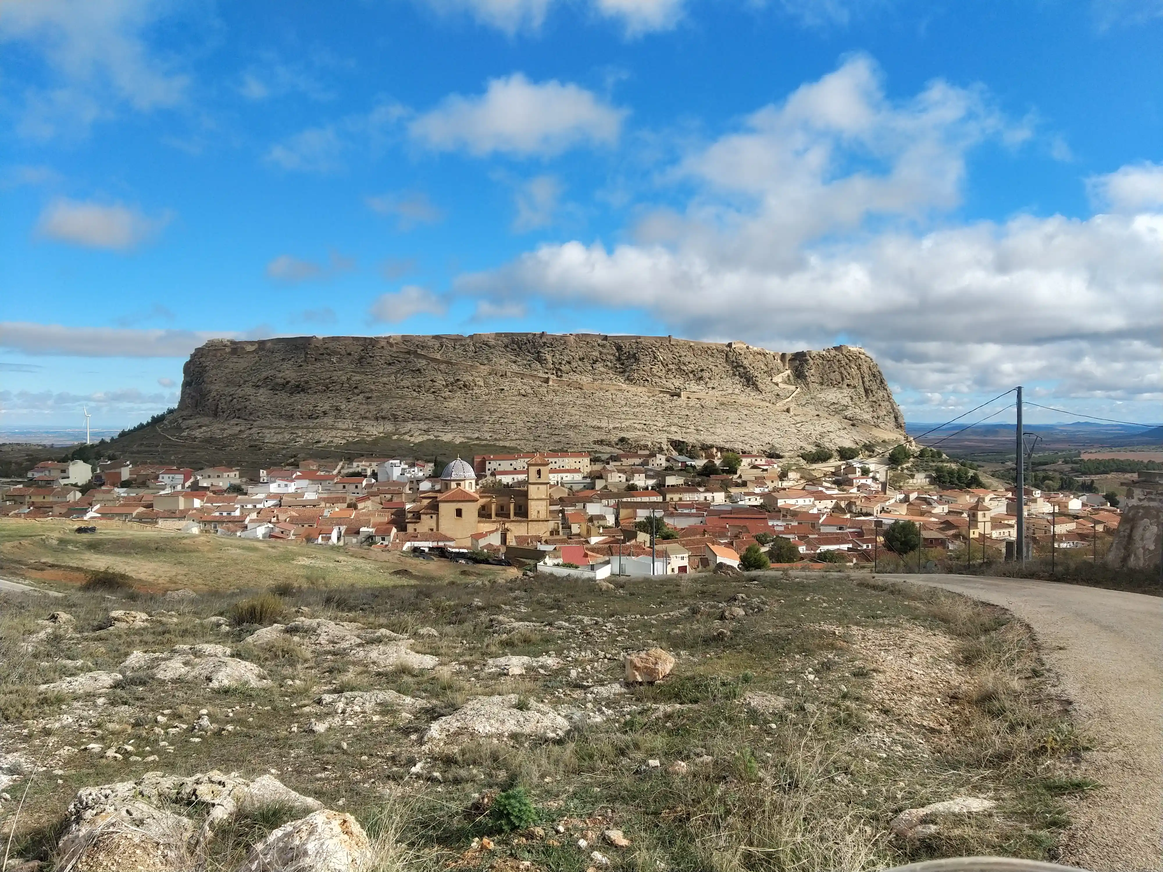 Village blotti au pied d’un plateau rocheux, vu depuis une piste