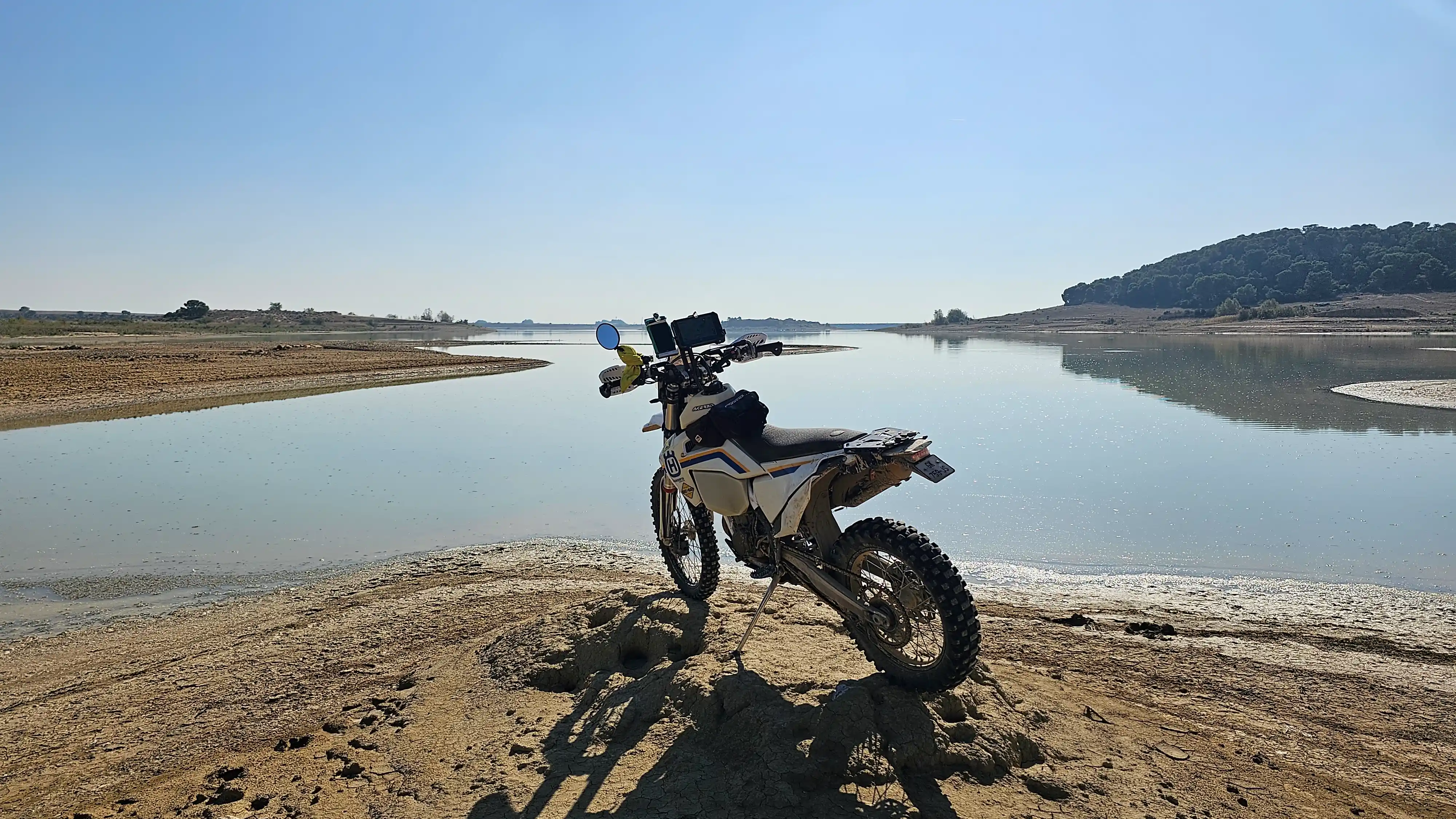 Moto d’enduro garée sur la rive sablonneuse d’un lac