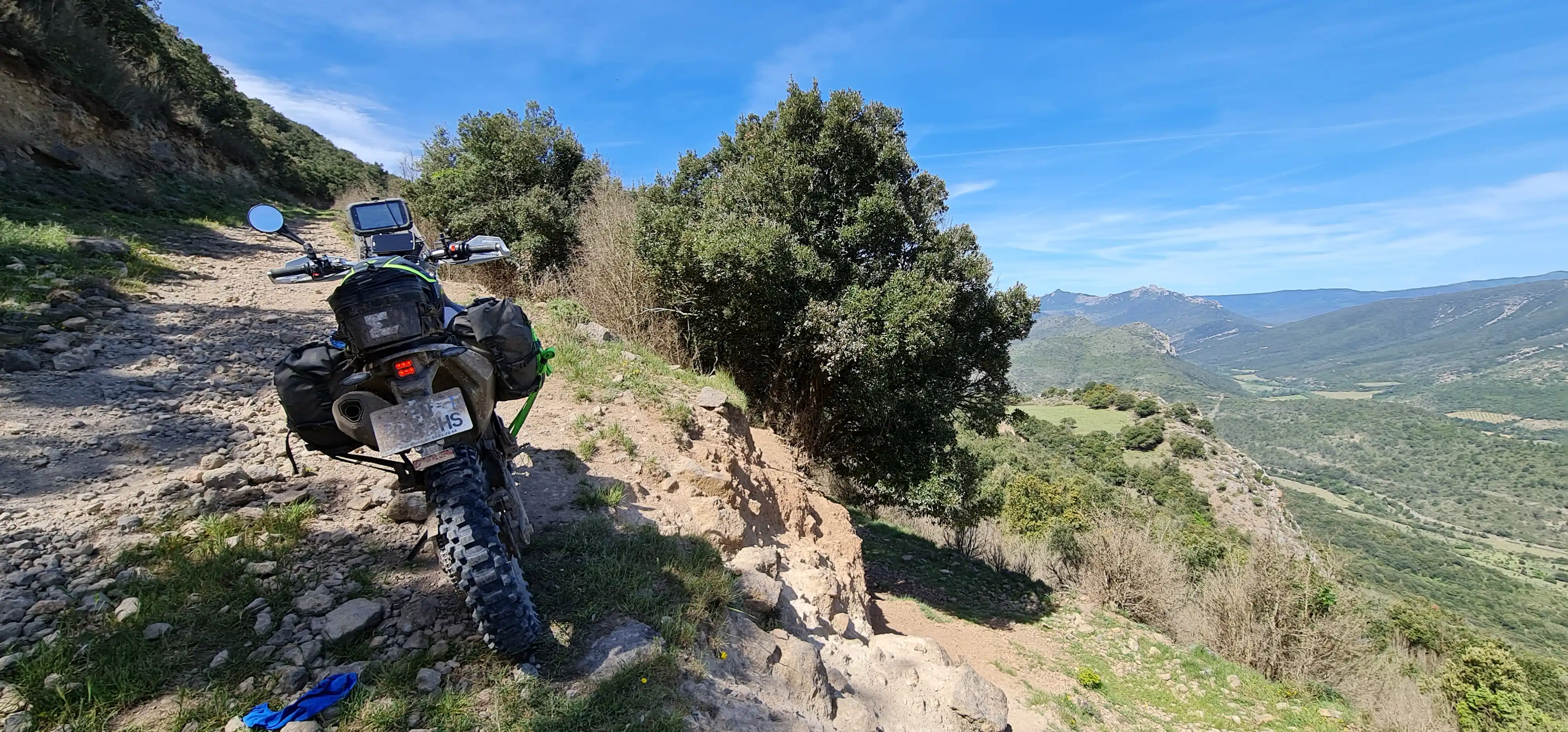 Moto trail garée sur un sentier rocheux dominant une vallée