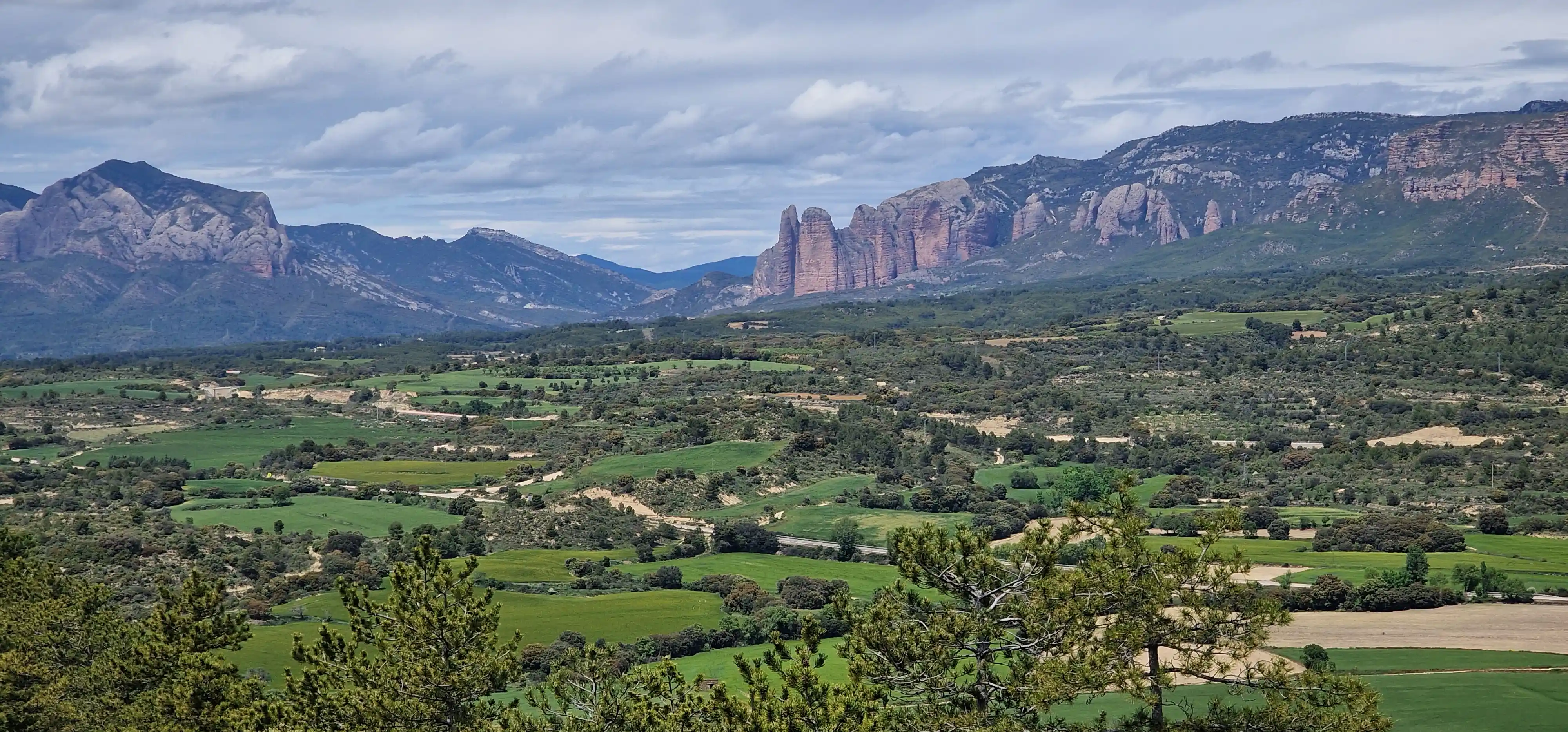 Vallée verdoyante dominée par les Mallos de Riglos
