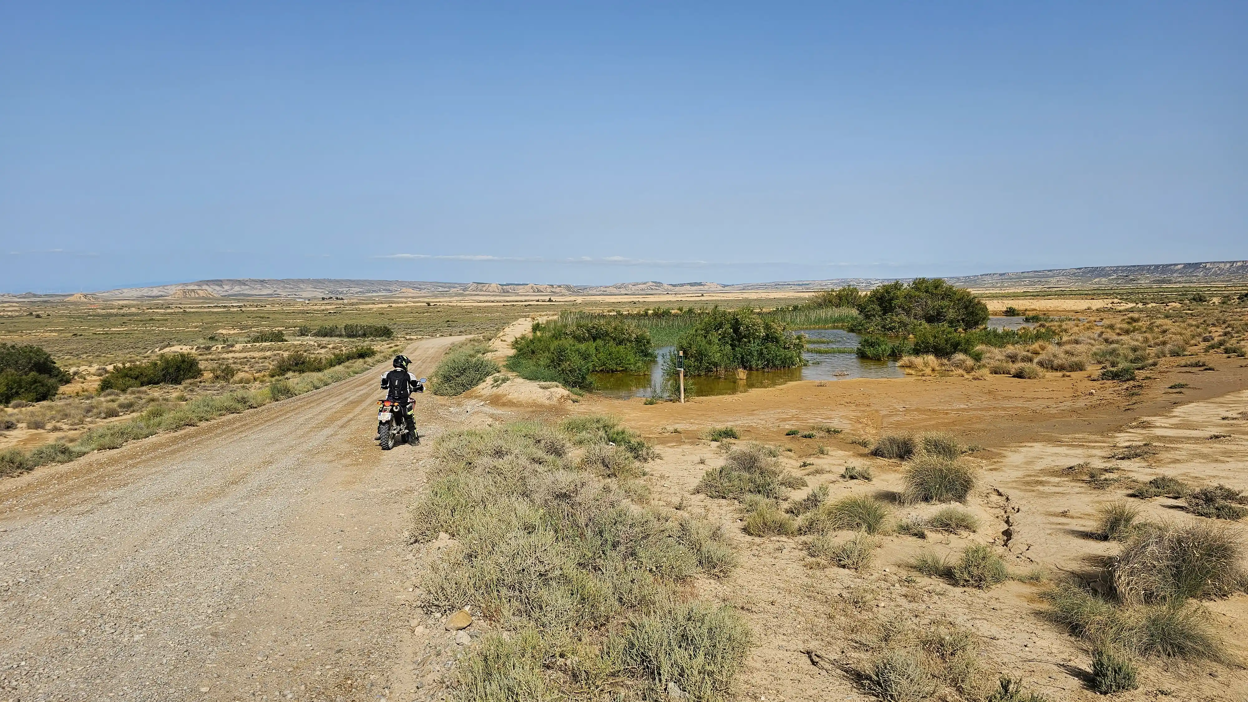 Motard trail sur une piste de terre en zone semi-désertique