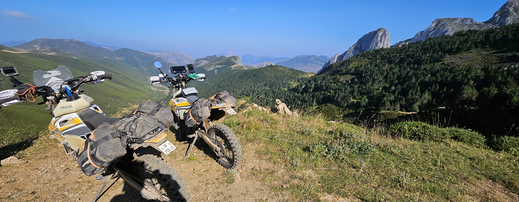 Motos trail garées sur une crête herbeuse face aux montagnes