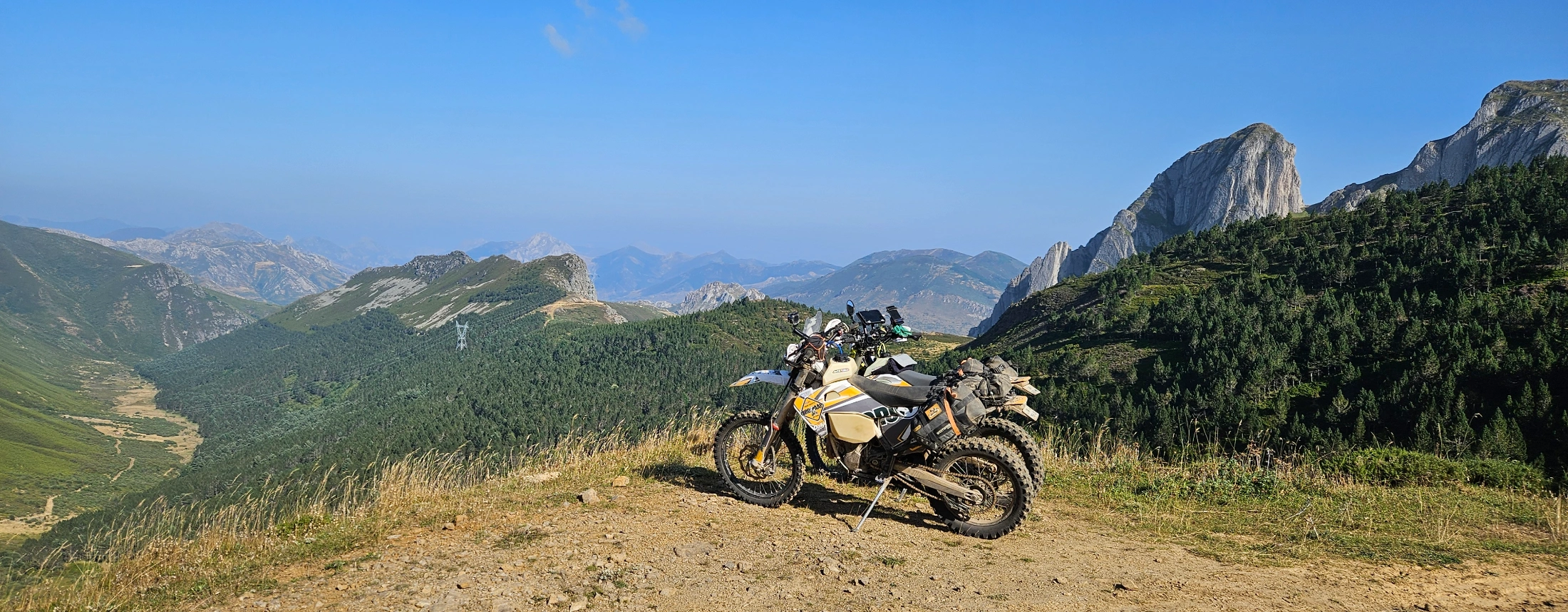 Moto trail garée sur une piste face à des sommets rocheux