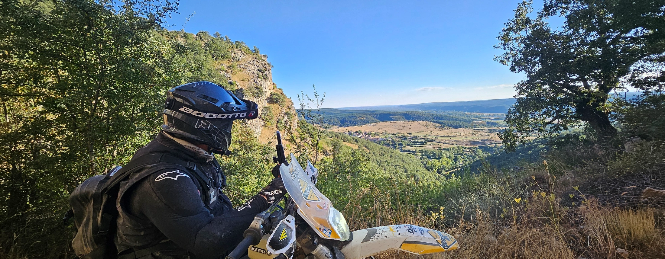 Motard trail casqué admirant un panorama sur une vallée