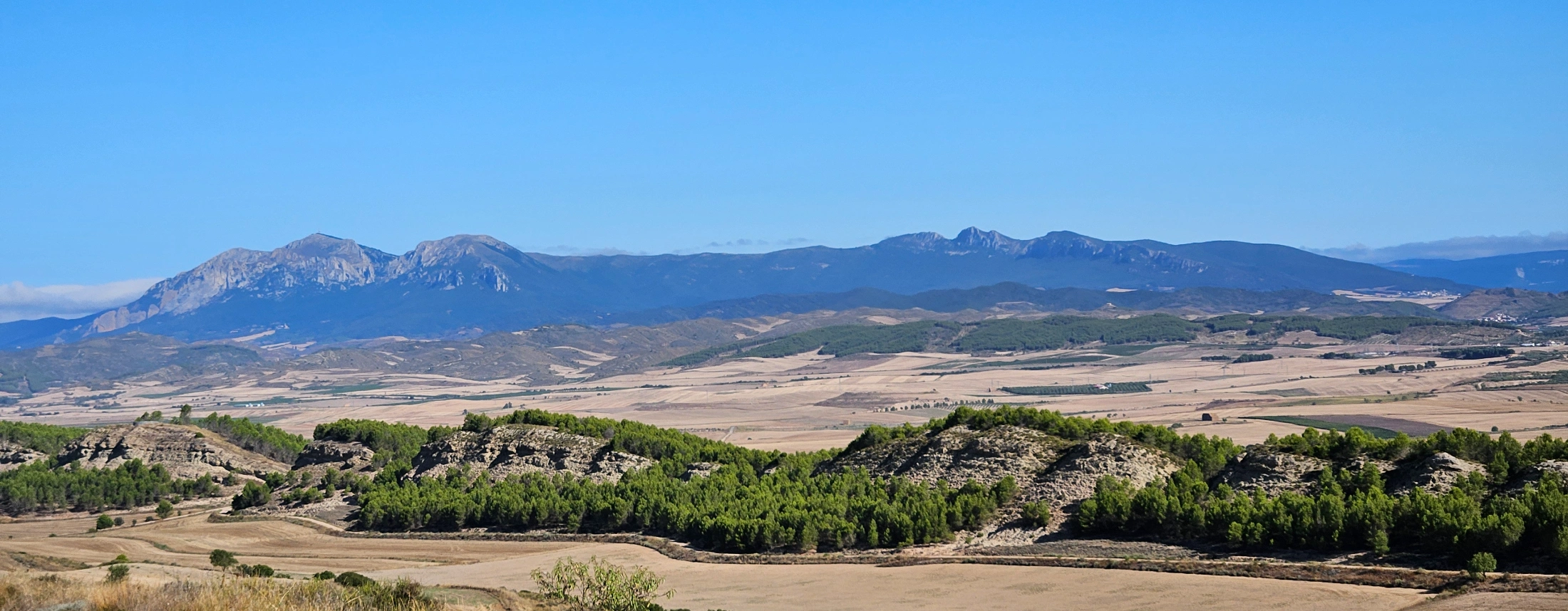 Plaine cultivée et montagnes à l’horizon sous un ciel bleu