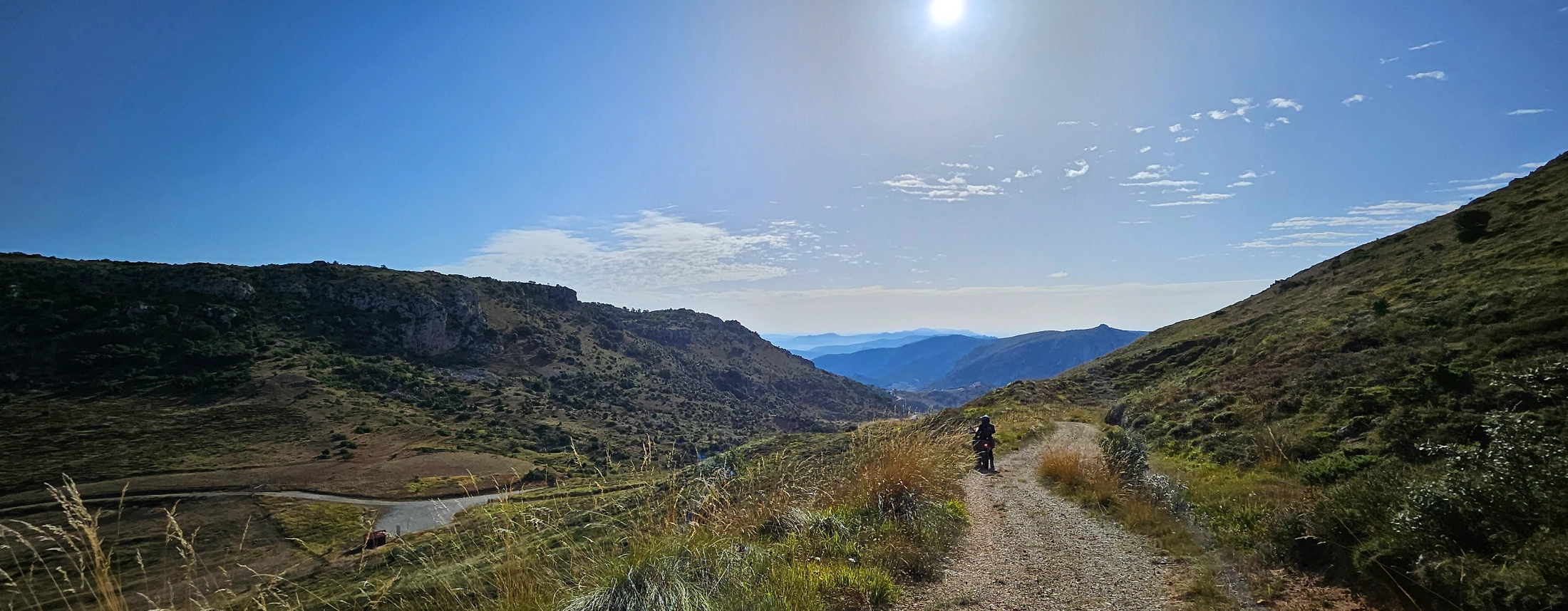 Motard trail sur une piste au fond d’une vallée ensoleillée